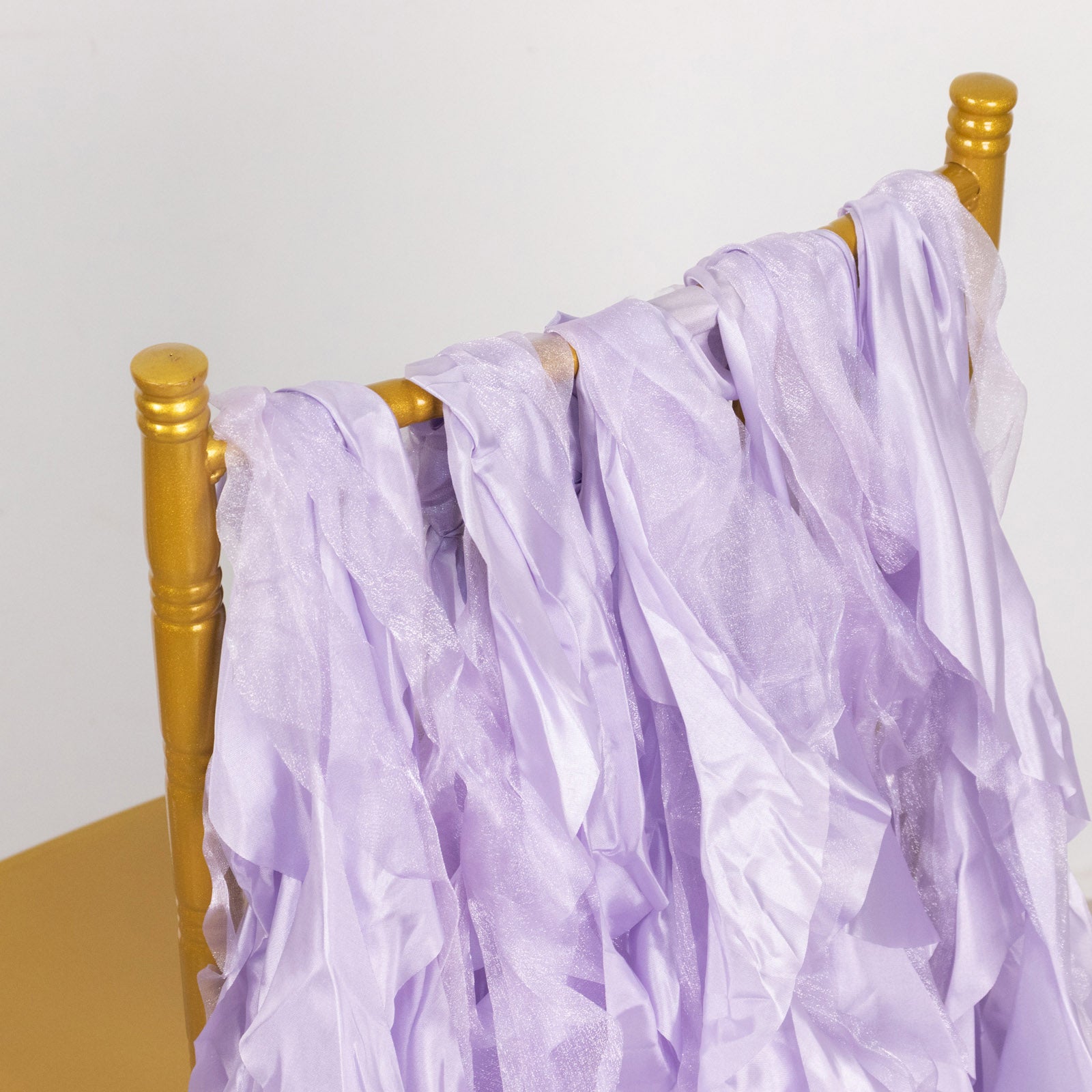 Lavender lilac chiffon satin chair sashes draped over a gold chair.