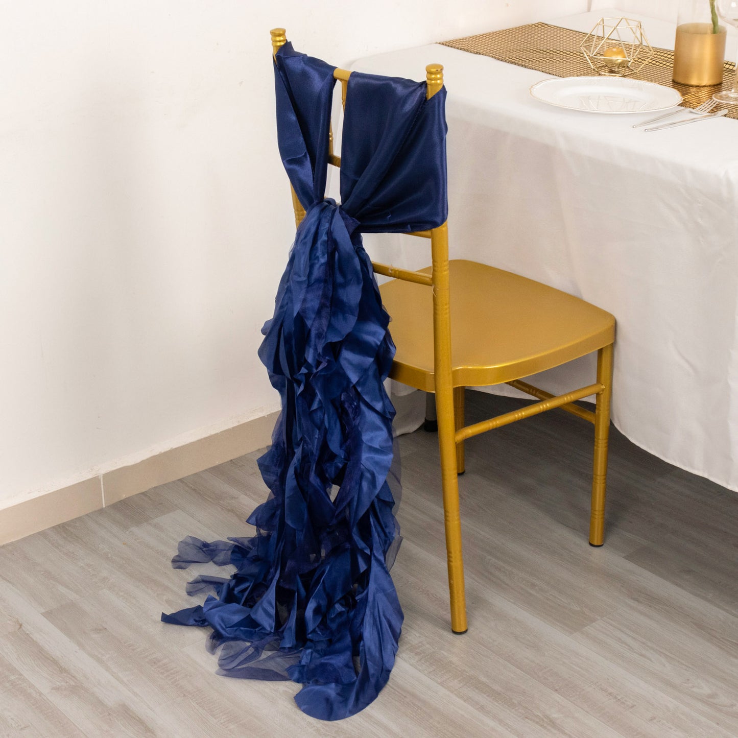 Navy blue curly chiffon satin chair sash draped on a gold chair.