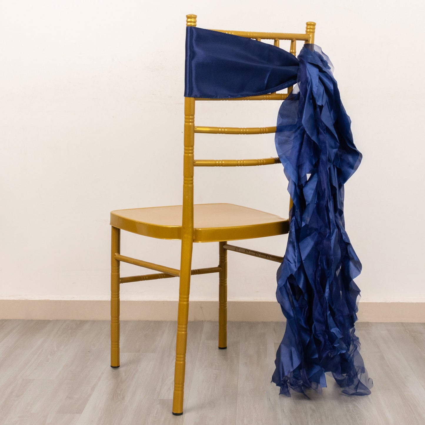 Navy blue curly chiffon satin chair sash on a gold chair.