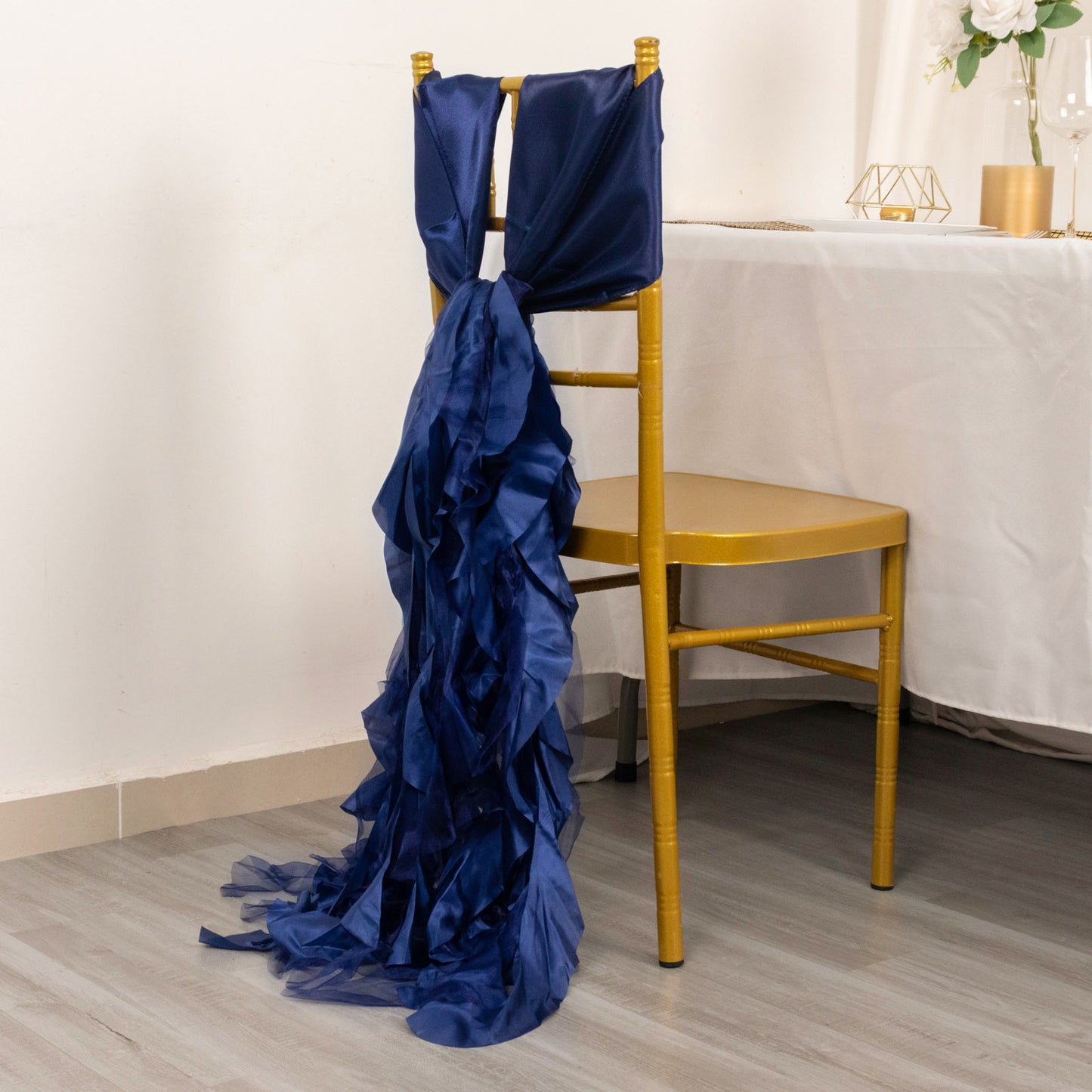 Navy blue chiffon satin chair sash elegantly draped on a gold chair.