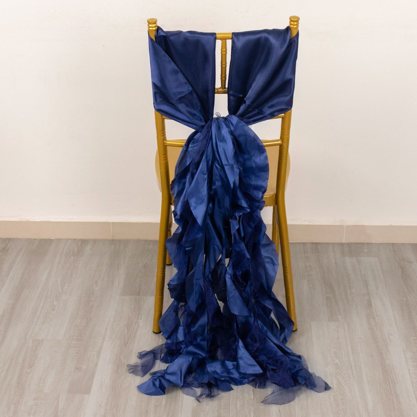 Navy blue curly chiffon satin chair sash on a gold chair.