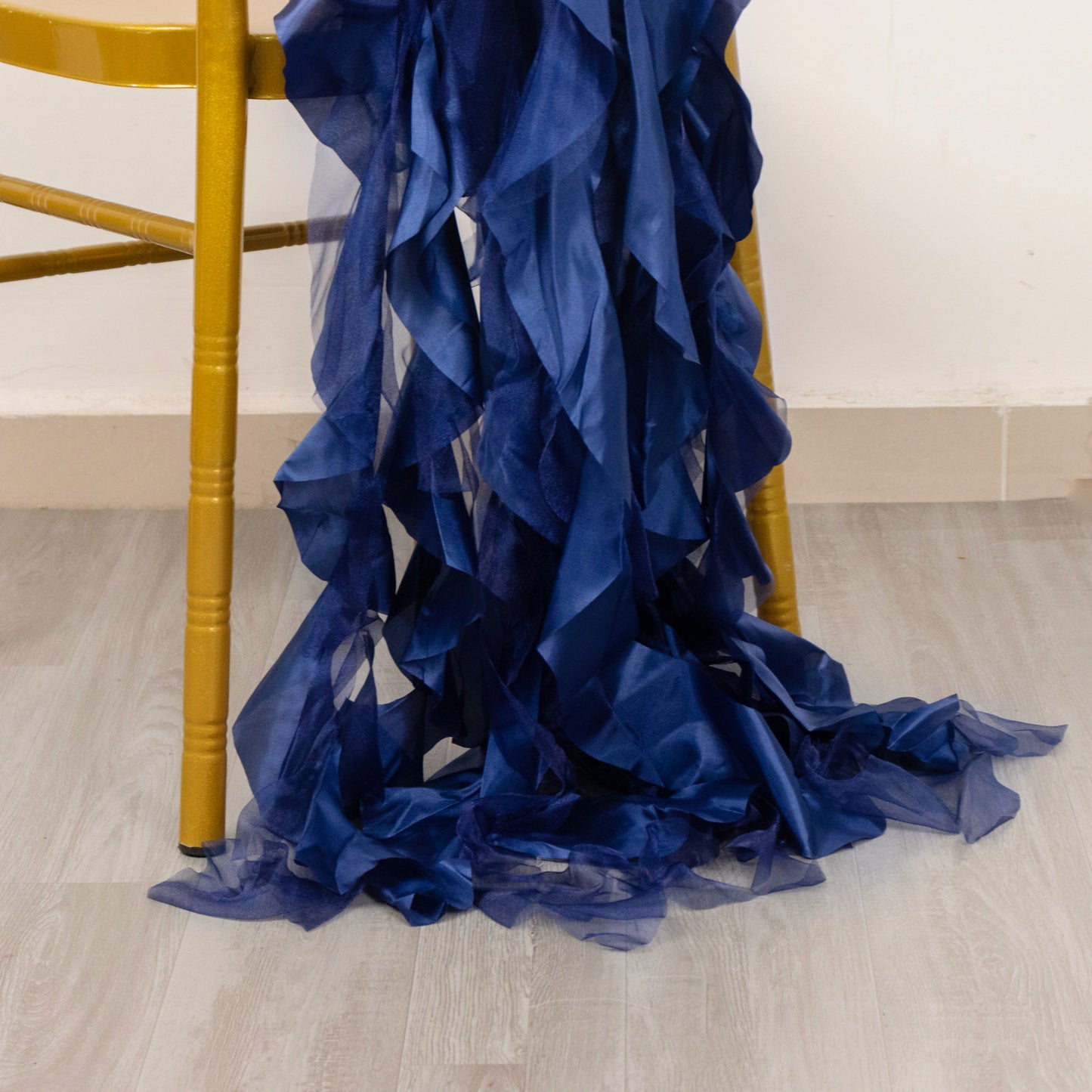Navy blue curly chiffon satin chair sashes draped on a chair leg.