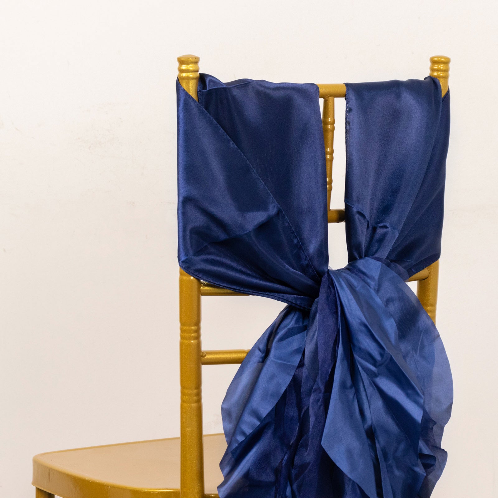 Navy blue curly chiffon satin chair sashes on a gold chair.
