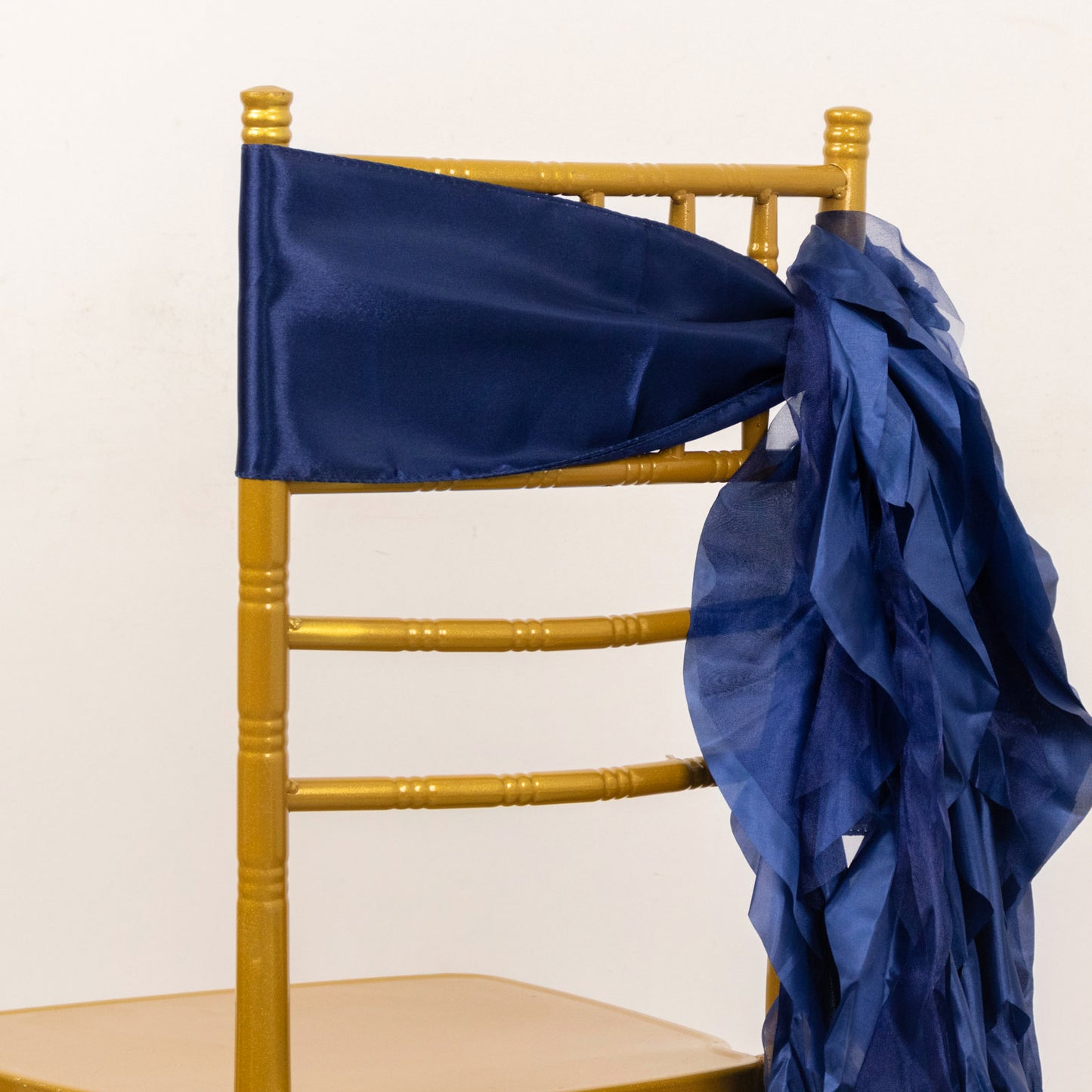 Navy blue chiffon satin chair sash elegantly draped on a gold chair.