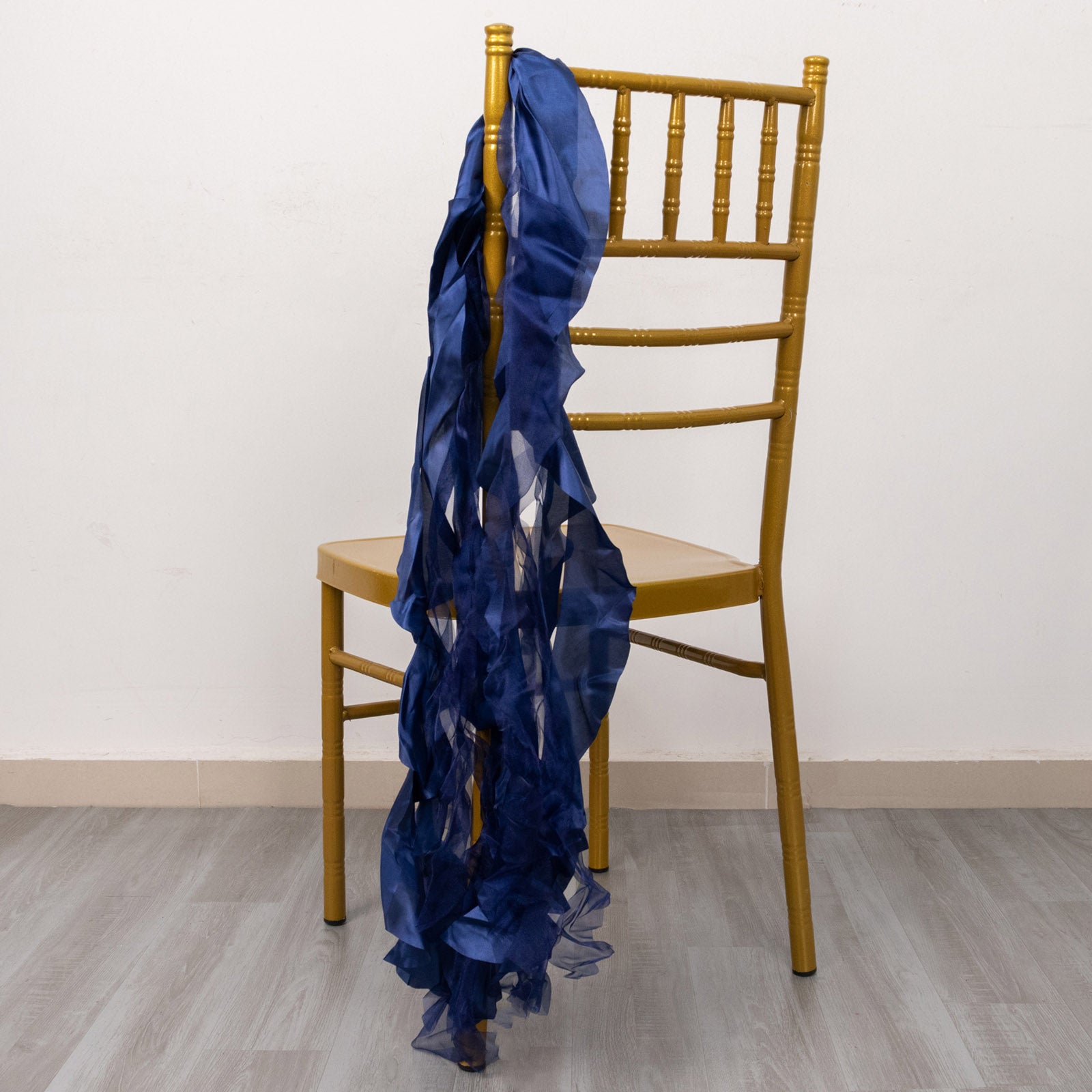 Navy blue chiffon satin chair sash draped on a gold chiavari chair.