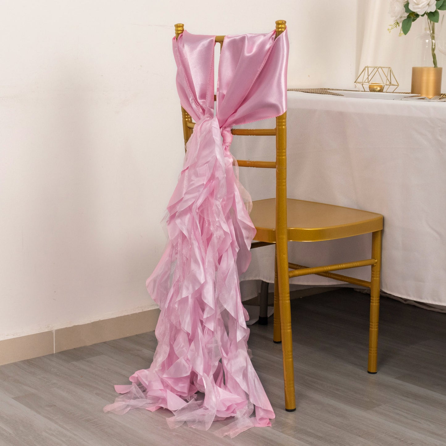 Pink chiffon satin chair sashes draped elegantly over a gold chair.