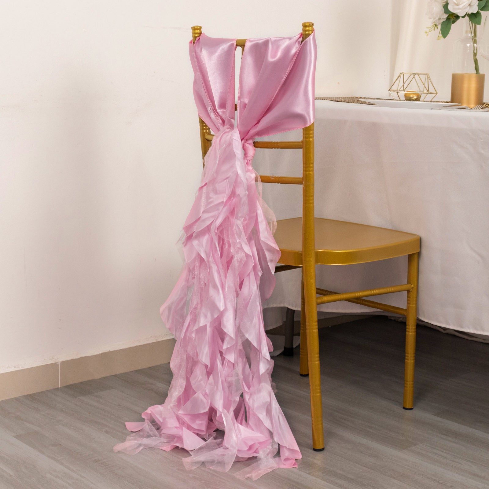 Pink chiffon satin chair sashes draped elegantly over a gold chair.