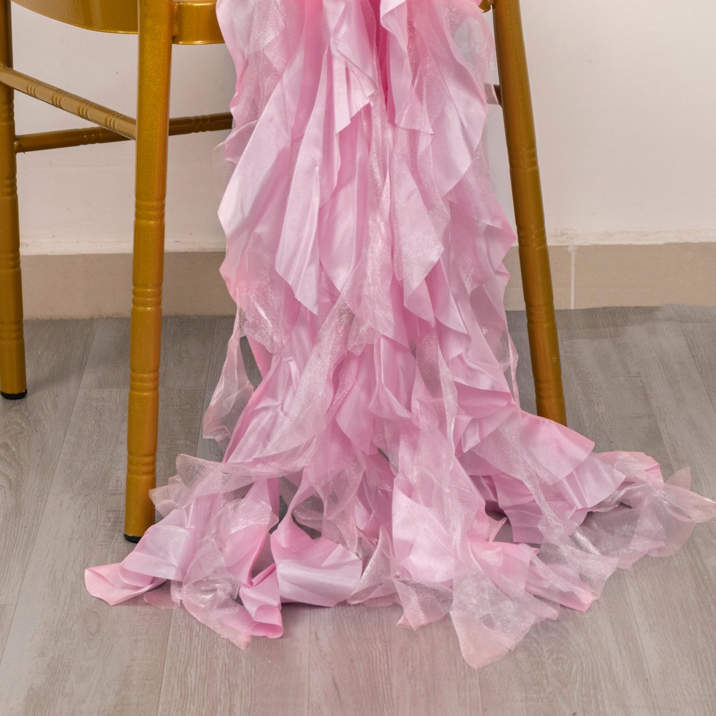 Pink chiffon satin chair sashes draped on a wooden chair.