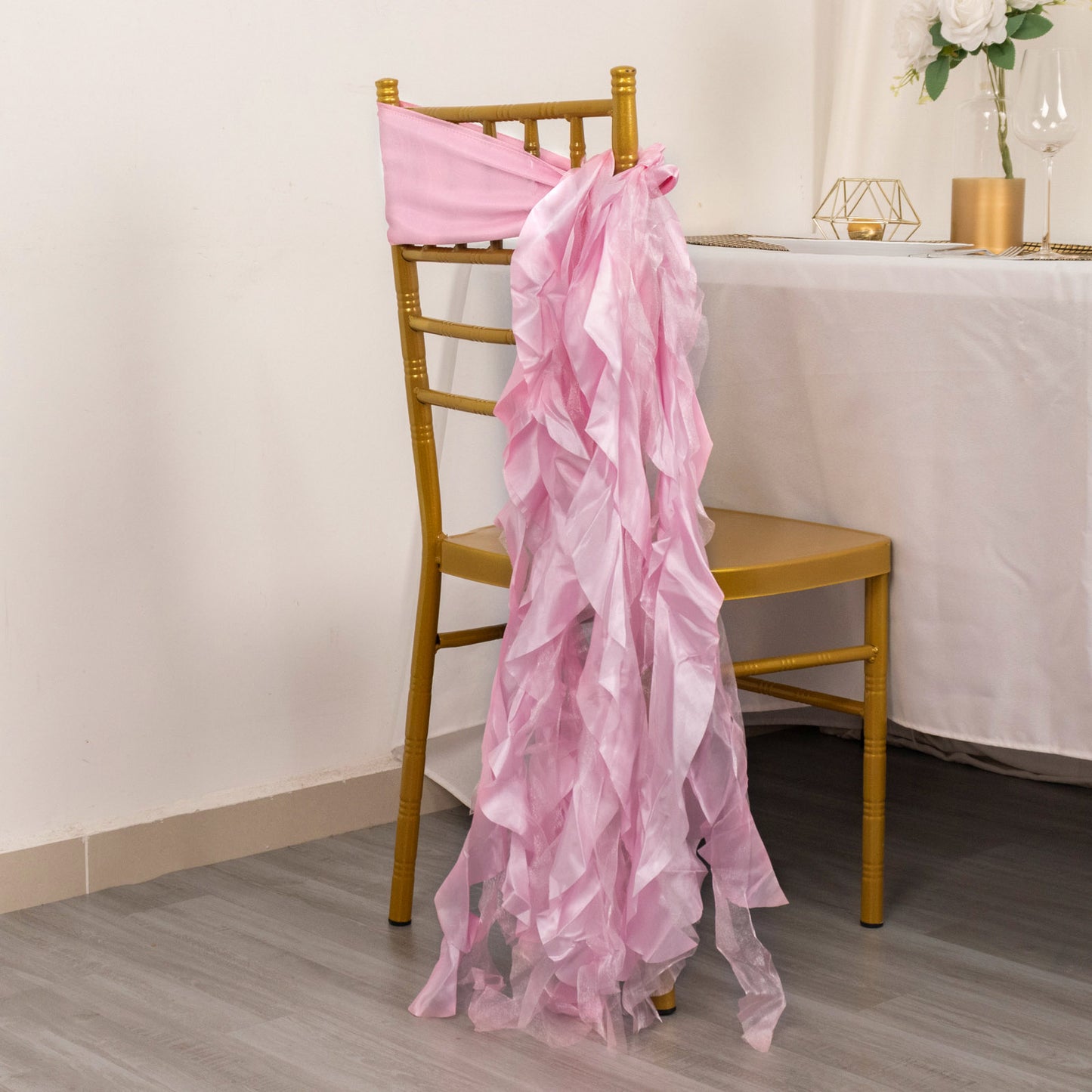 Pink chiffon satin chair sashes draping over a gold chair.