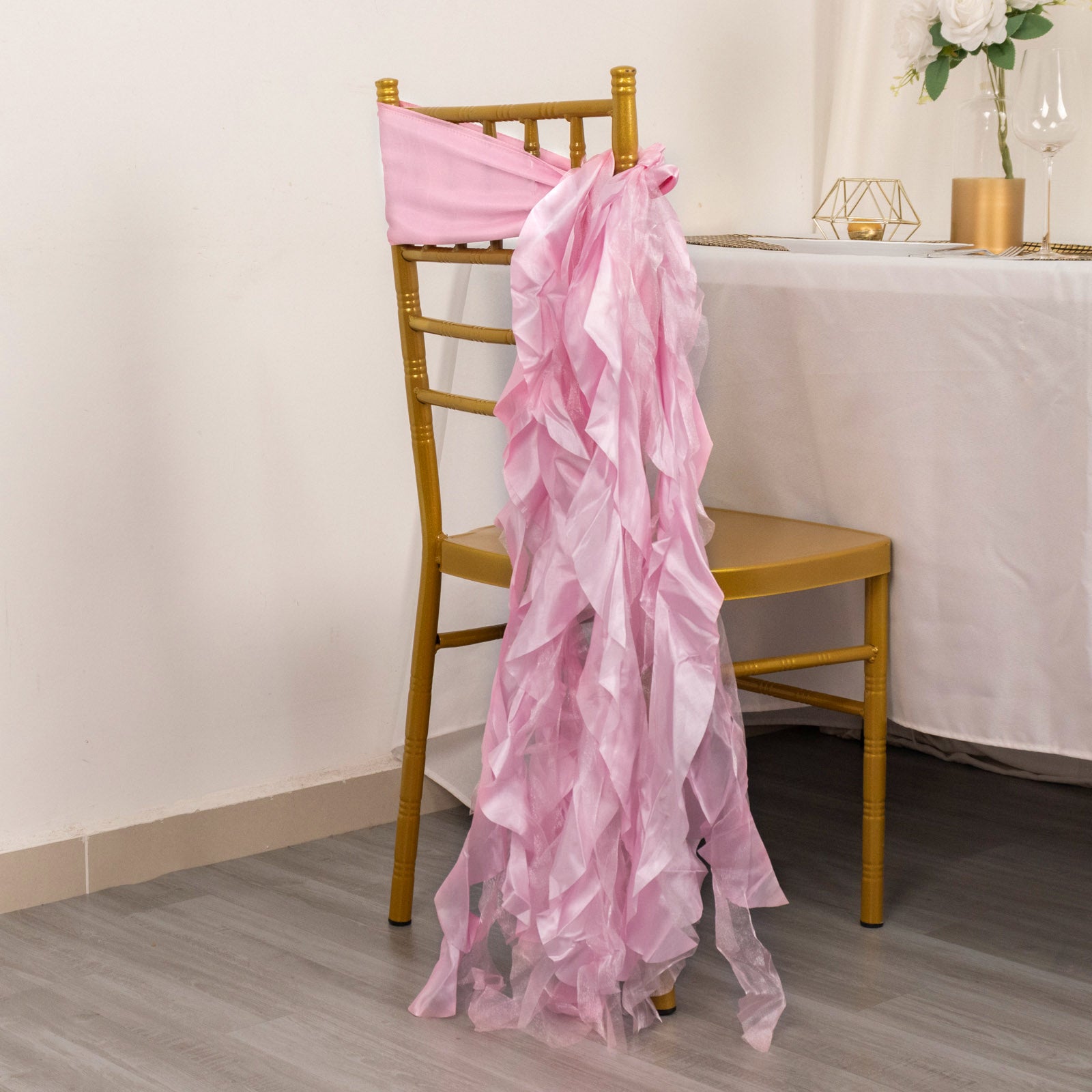 Pink chiffon satin chair sashes draping over a gold chair.
