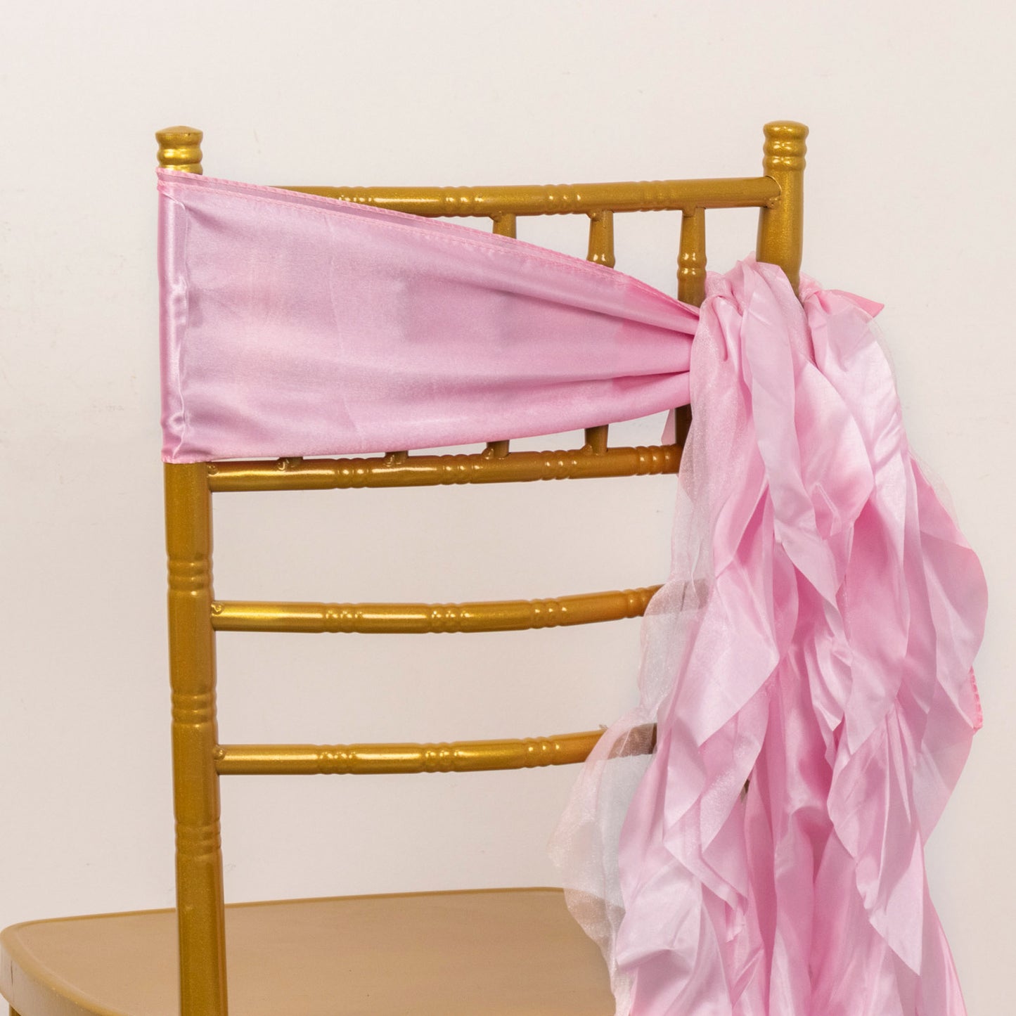 Pink chiffon satin chair sashes tied on a gold chiavari chair.