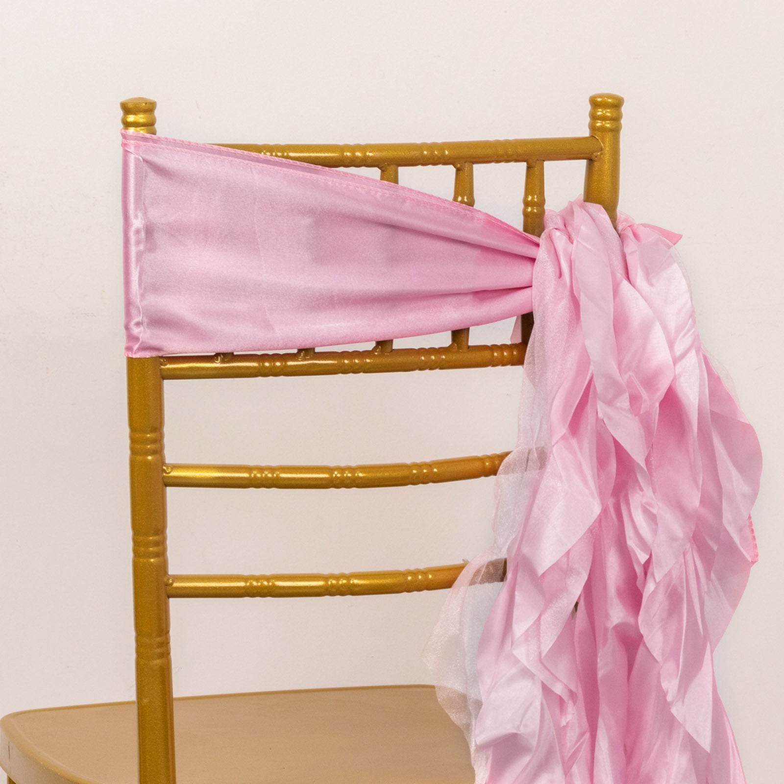 Pink chiffon satin chair sashes tied on a gold chiavari chair.