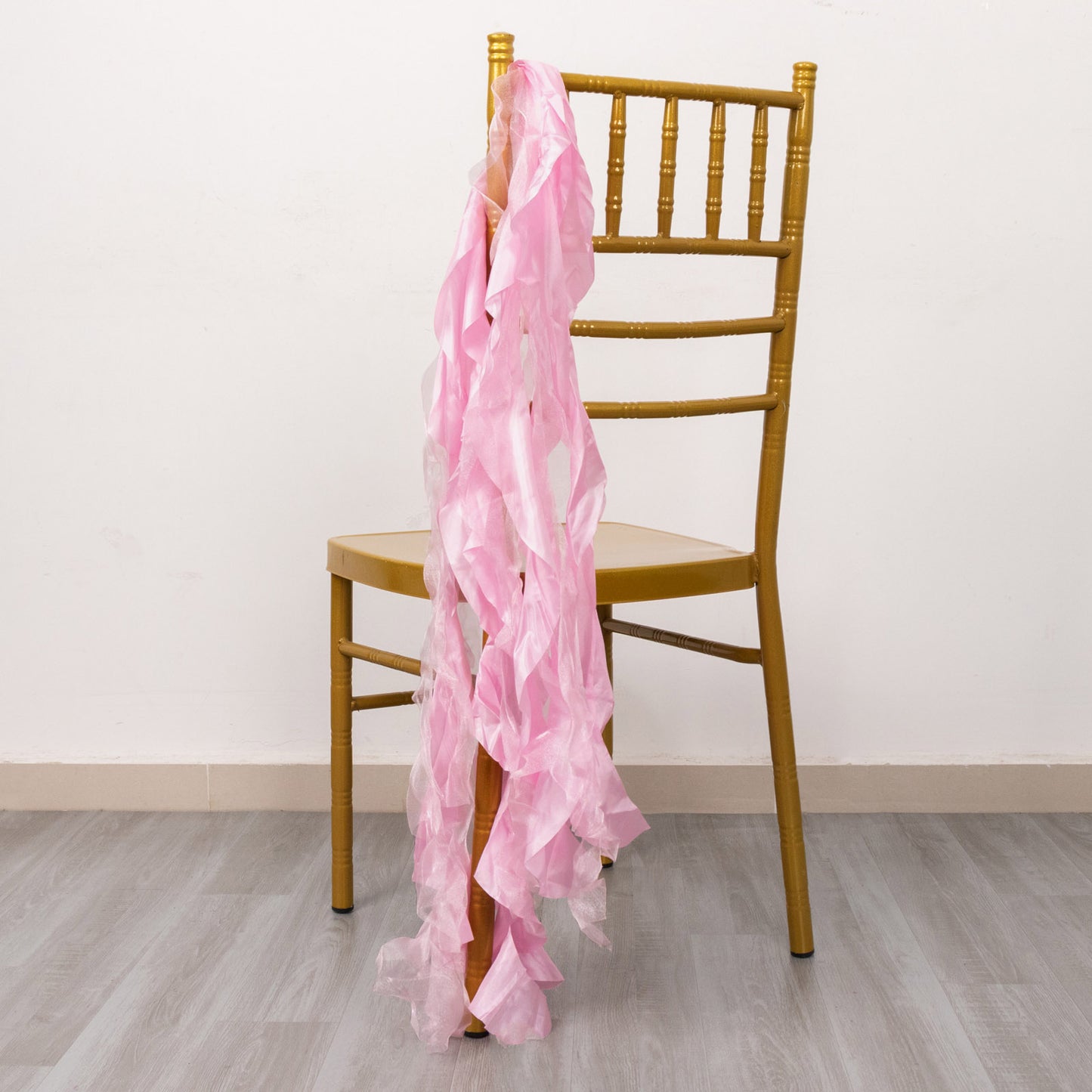 Pink curly chiffon satin chair sashes draped on a gold chiavari chair.