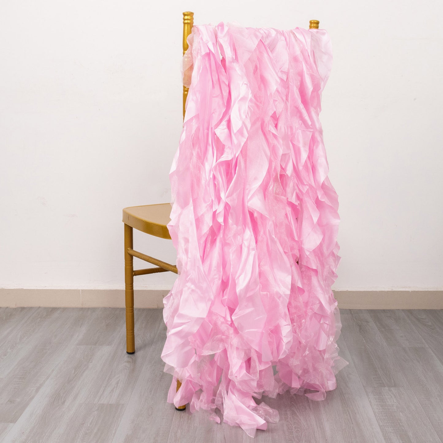 Pink chiffon satin chair sashes draped over a gold chair.