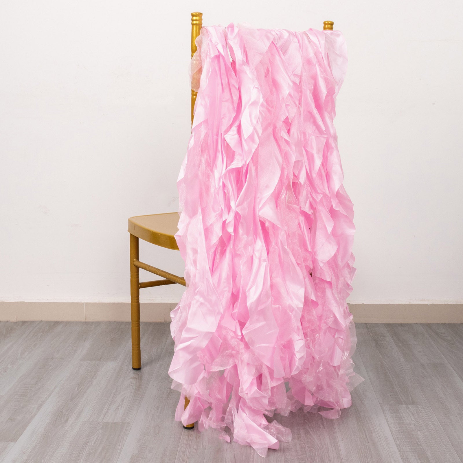 Pink chiffon satin chair sashes draped over a gold chair.