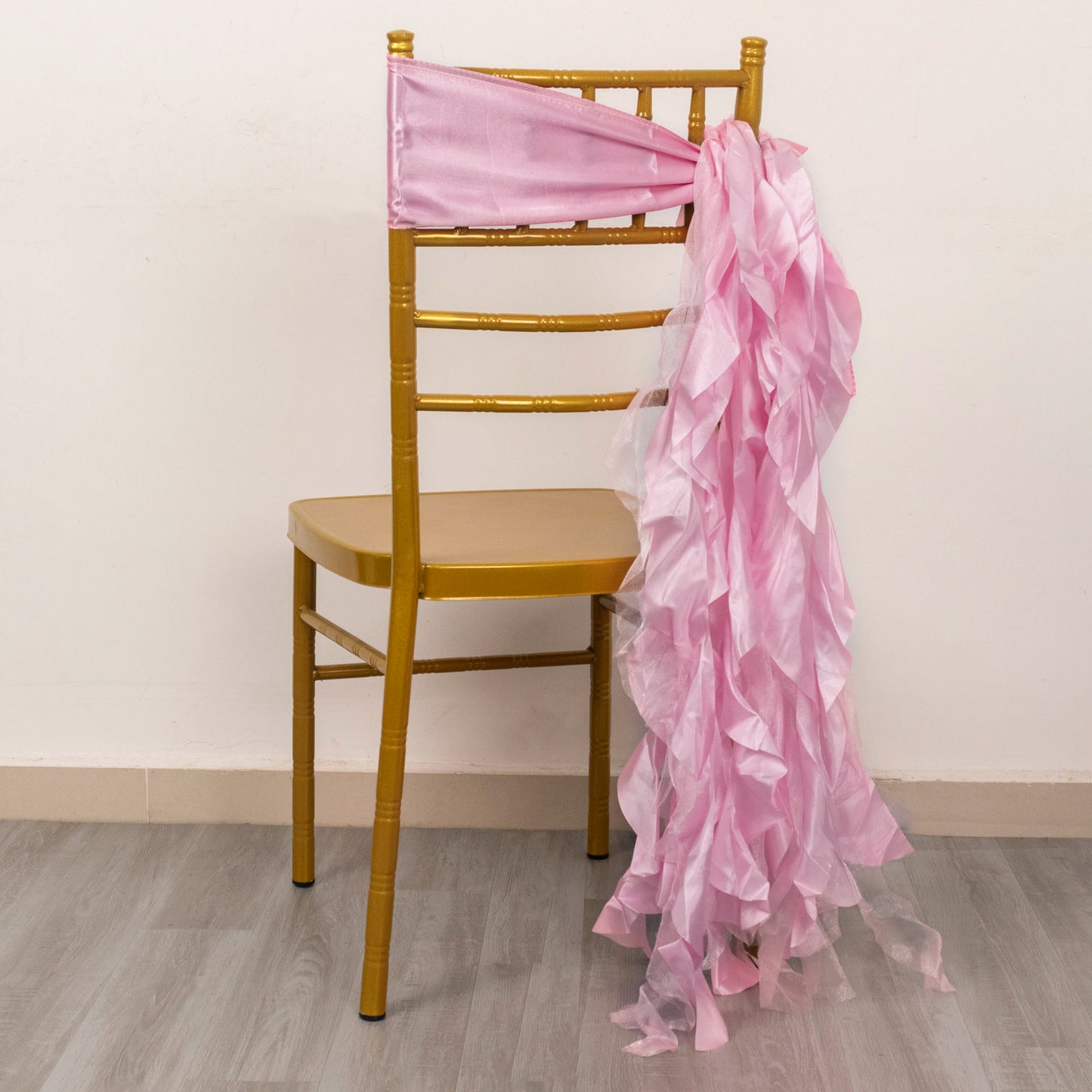 Pink chiffon satin chair sash draped on a gold chiavari chair.