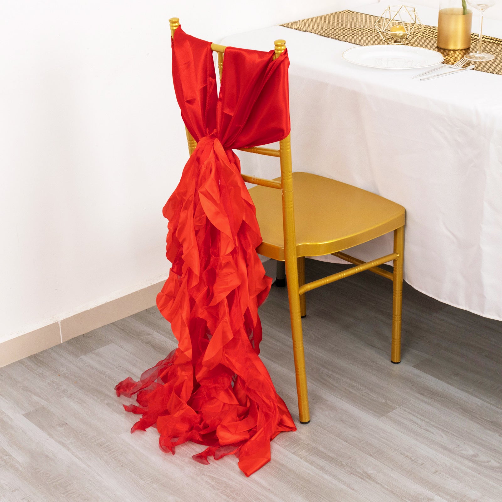Red chiffon satin chair sashes elegantly draped on a gold chair.