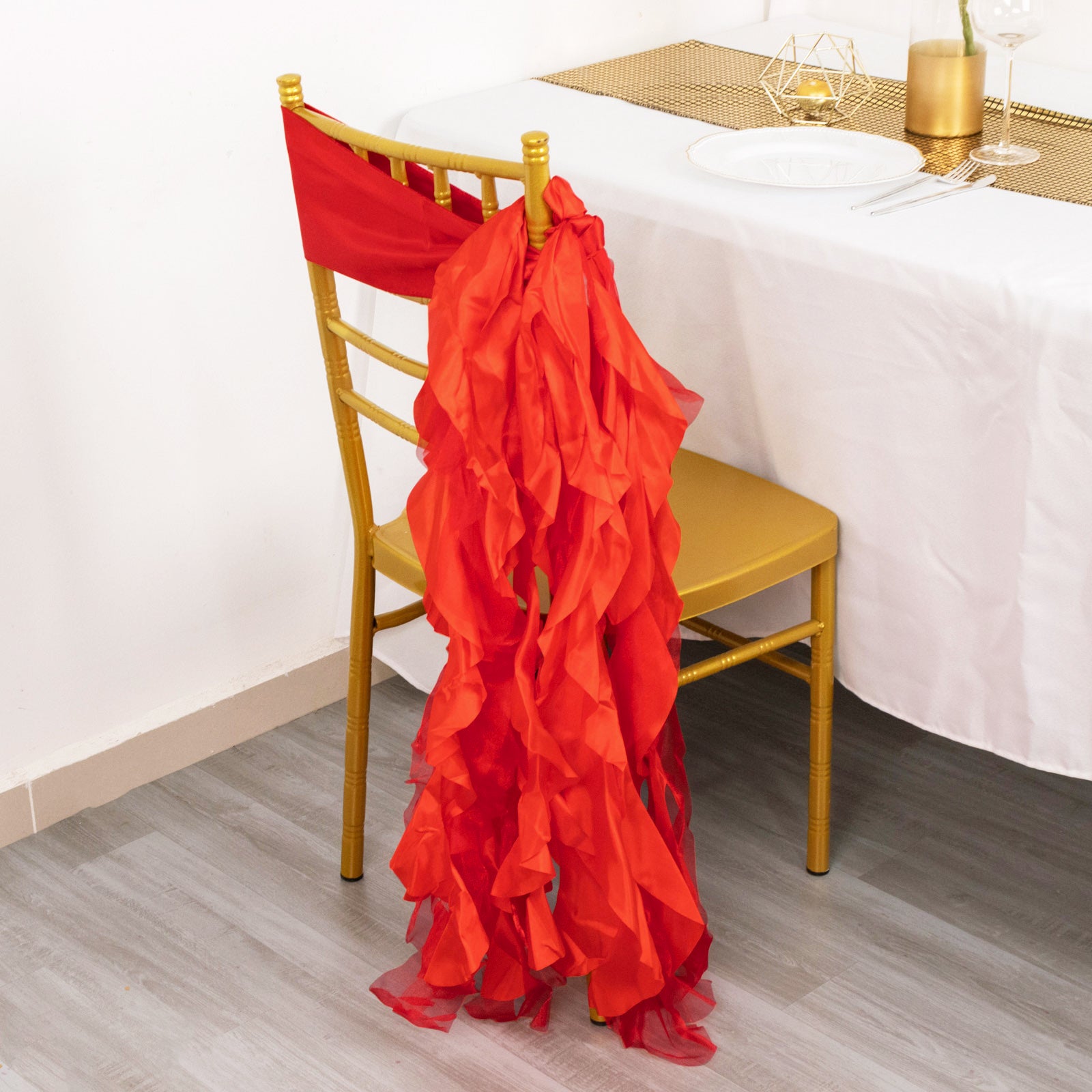Red chiffon satin chair sash draped on a gold chair.