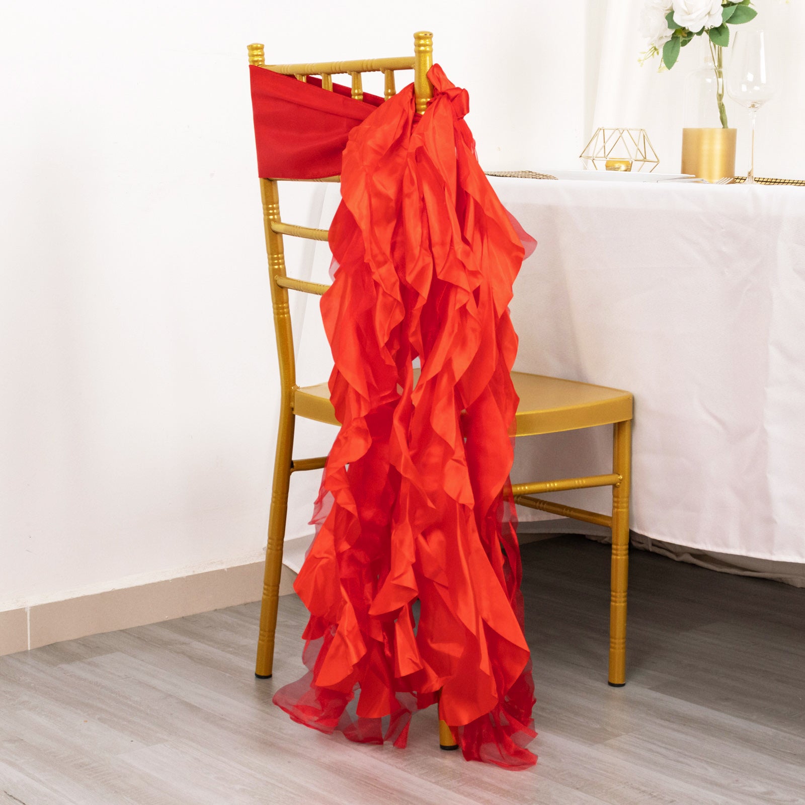 Red curly chiffon satin chair sash on a gold chair.