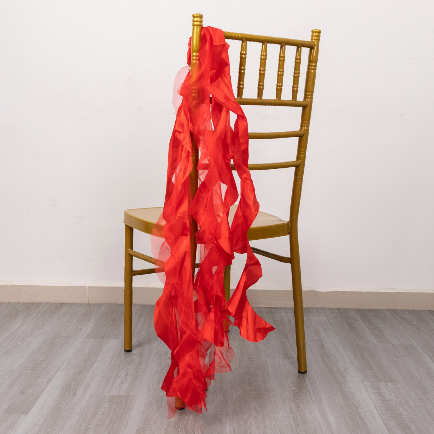 Red chiffon satin chair sashes draped on a gold chiavari chair.