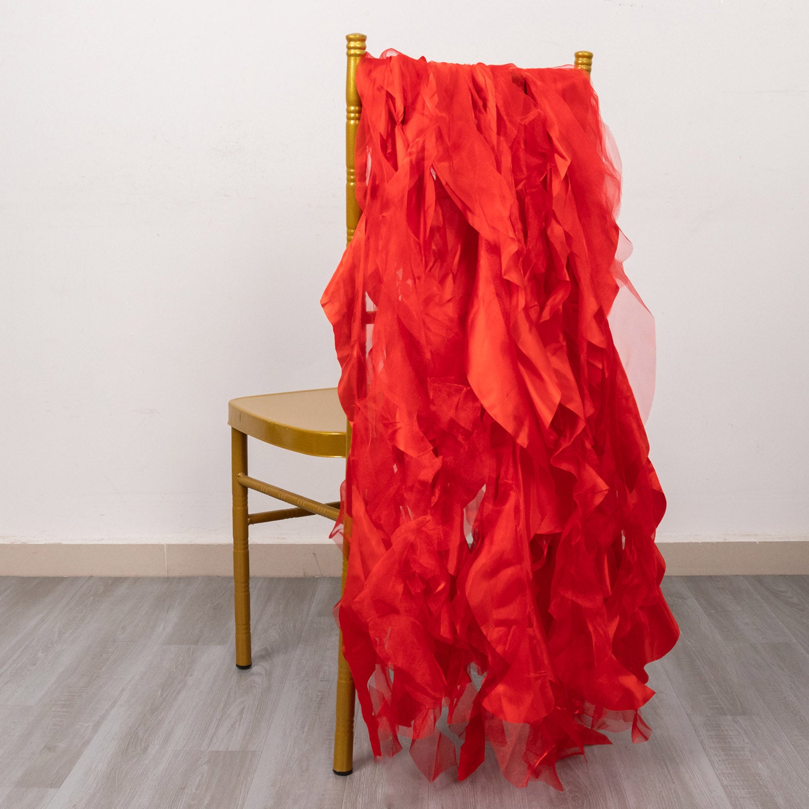 Red curly chiffon satin chair sashes draped over a gold chair.
