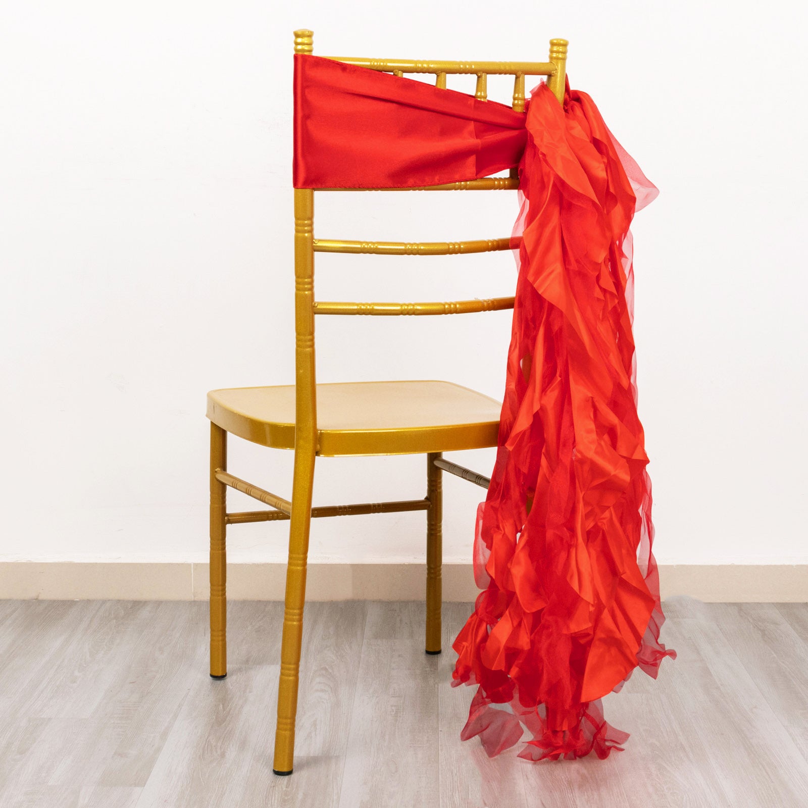 Red curly chiffon satin chair sash draped on a gold chair.