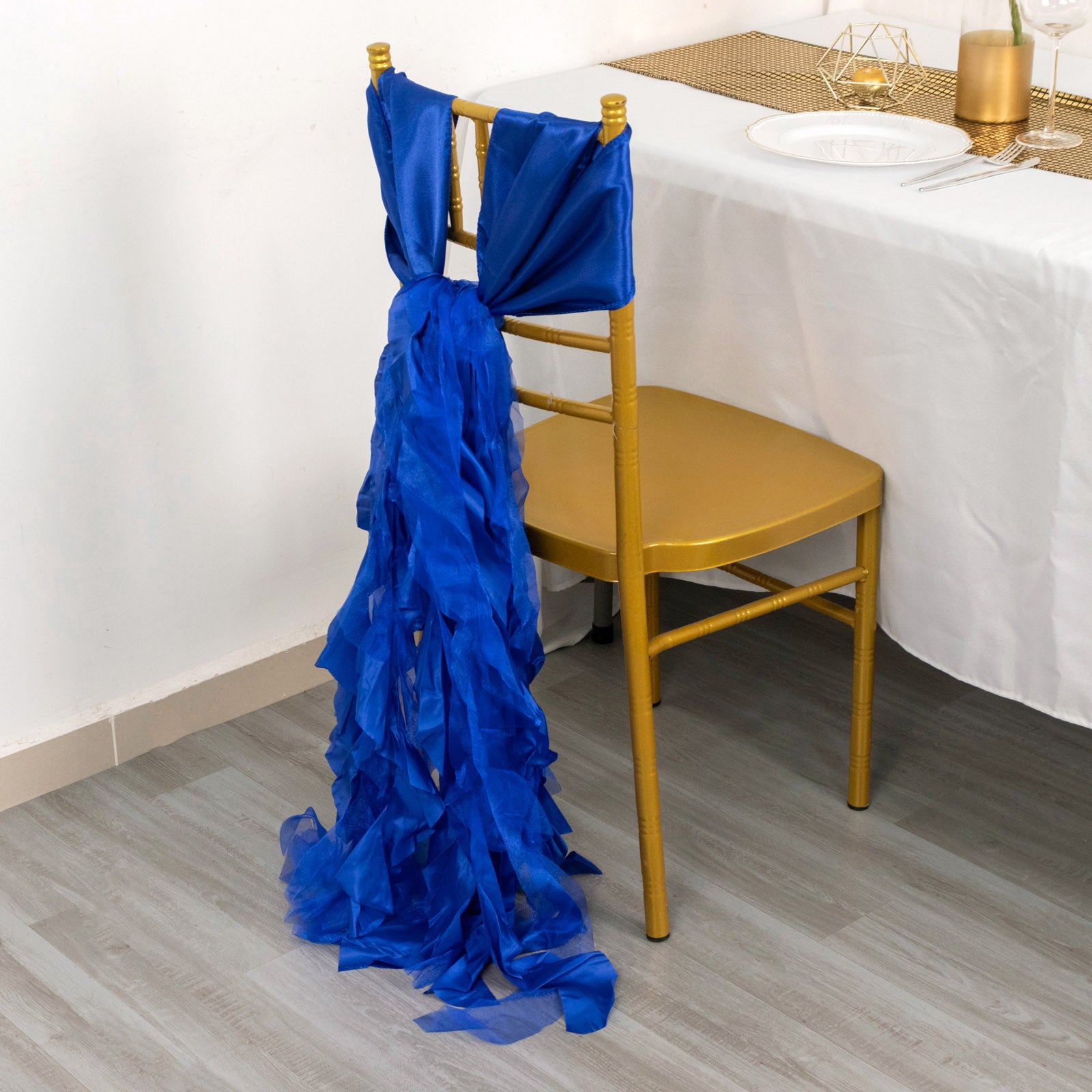 Royal blue chiffon satin chair sash draped elegantly on a gold chair.