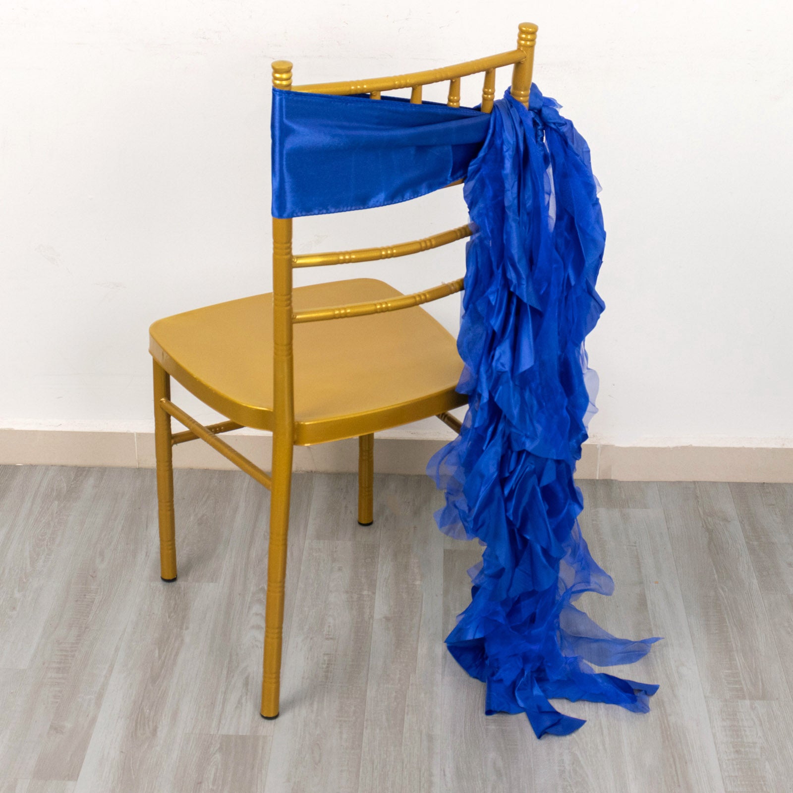 Royal blue chiffon satin chair sash draped over a gold chair.