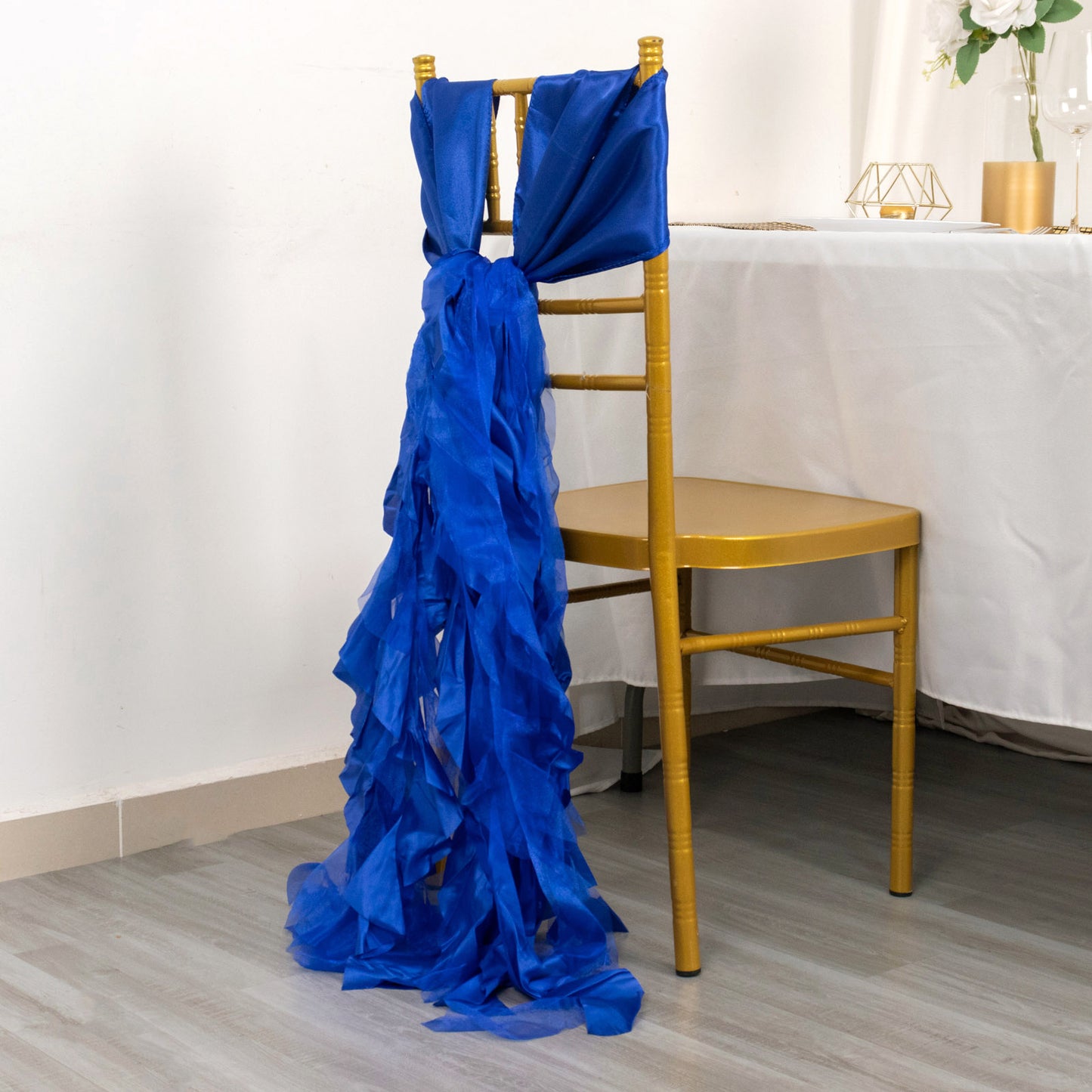 Royal blue chiffon satin chair sash draped on a gold chair.