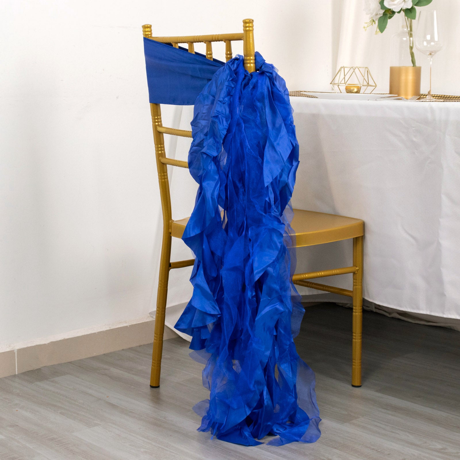 Royal blue chiffon satin chair sash draped on a gold chair.