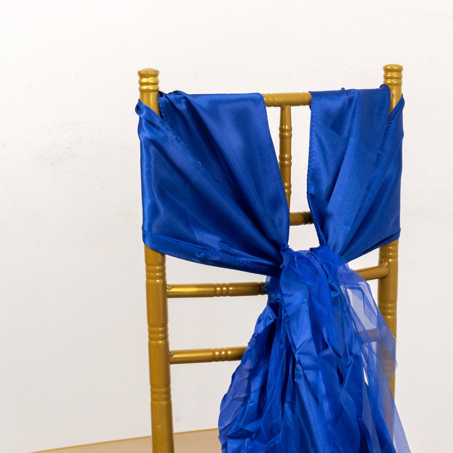 Royal blue chiffon satin chair sashes draped on a gold chair.