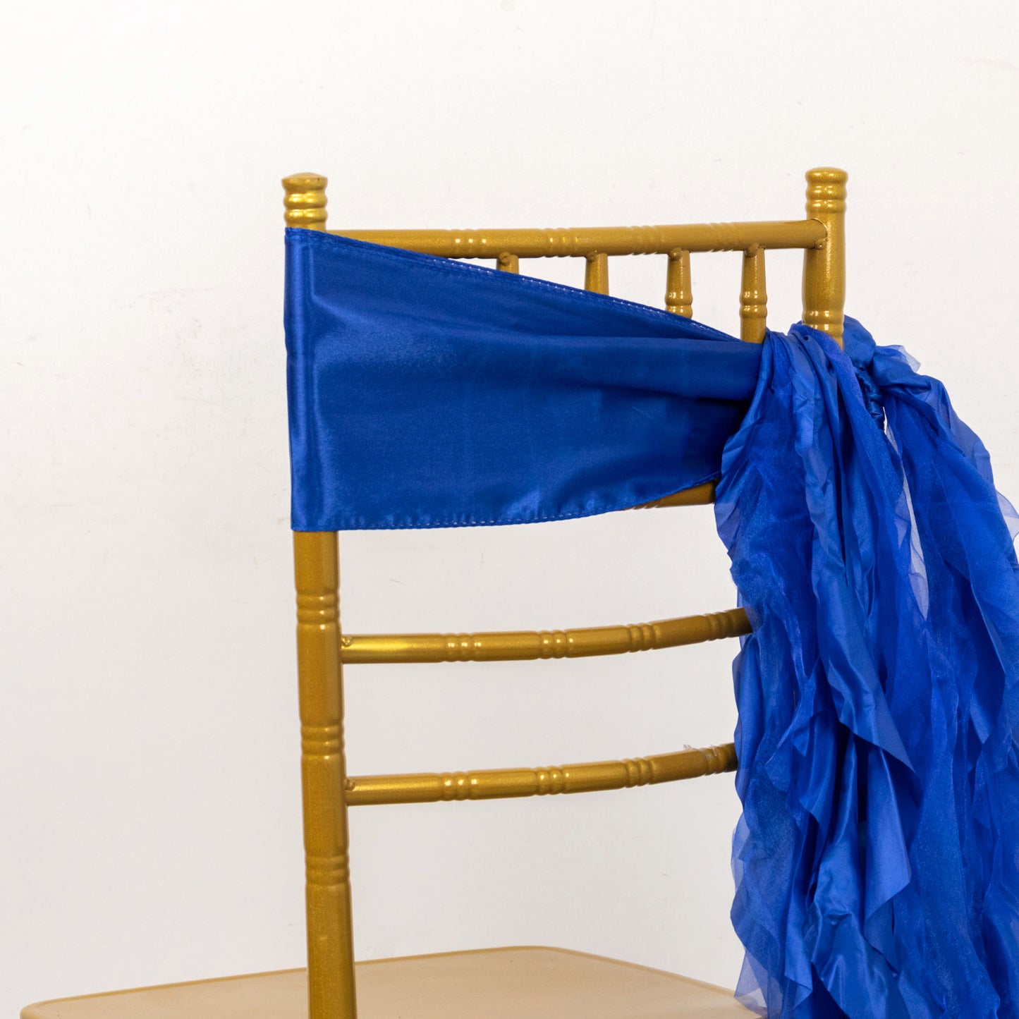 Royal blue chiffon satin chair sash tied on a gold chair.