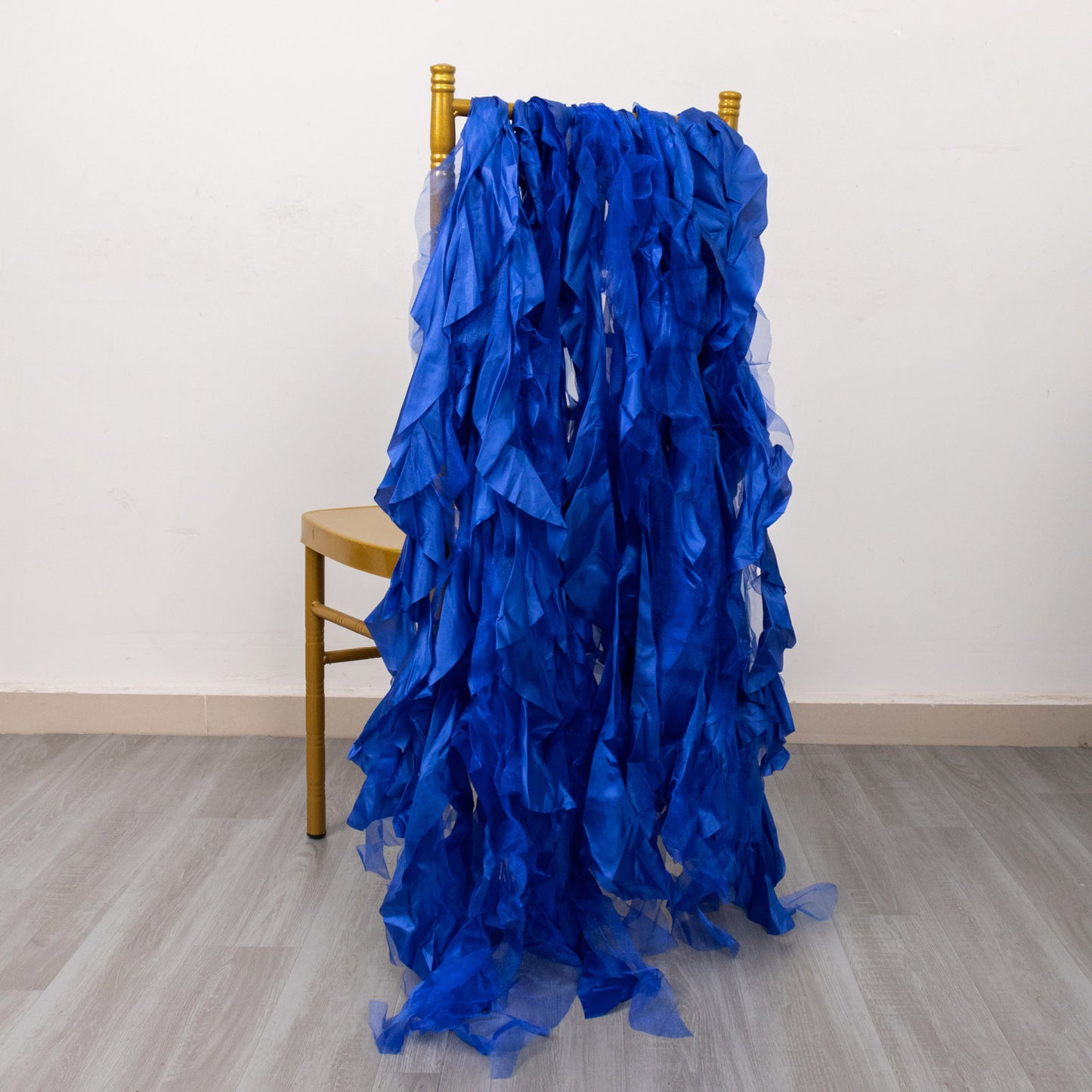Royal blue curly chiffon satin chair sashes draped over a chair.