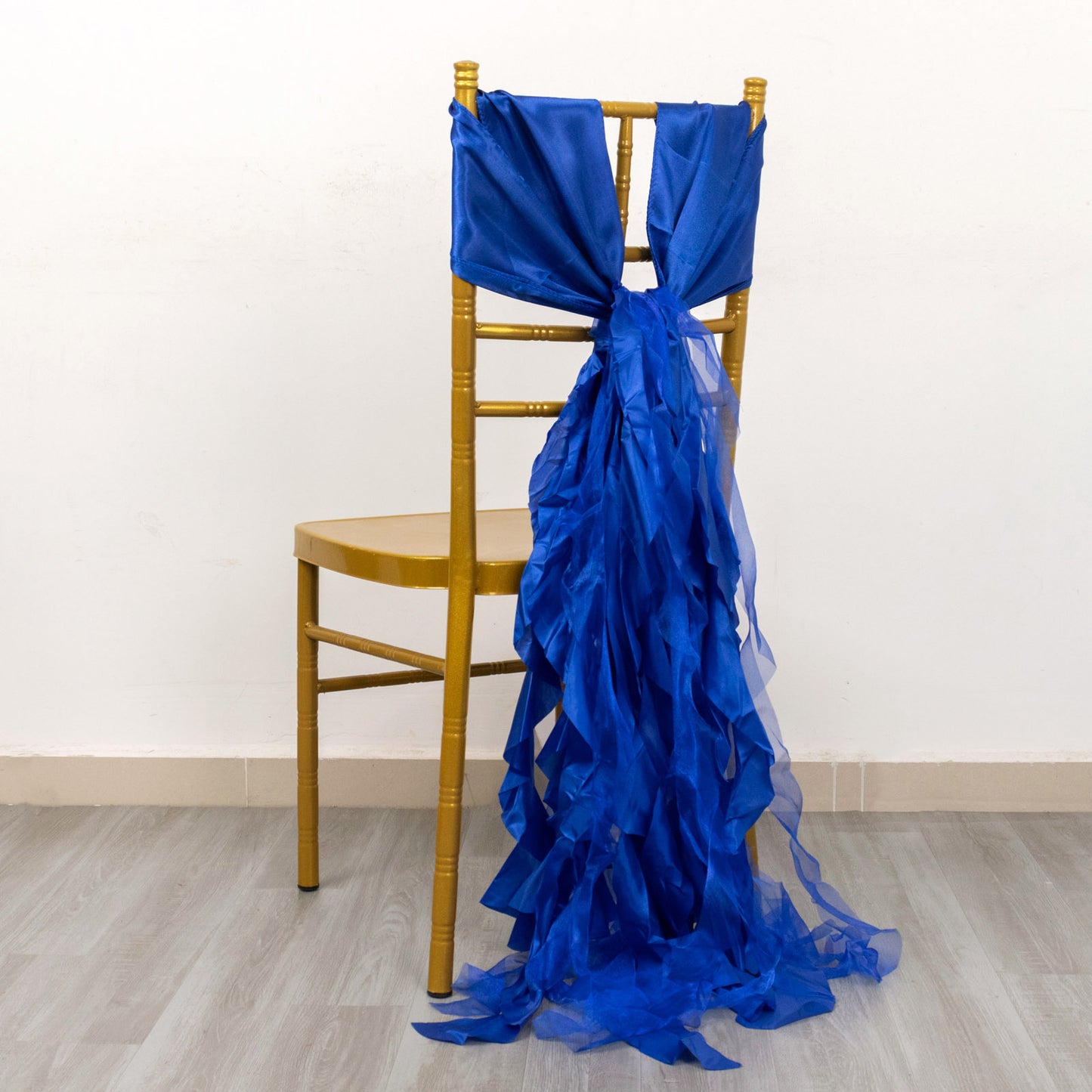 Royal blue curly chiffon satin chair sash on a gold chair.