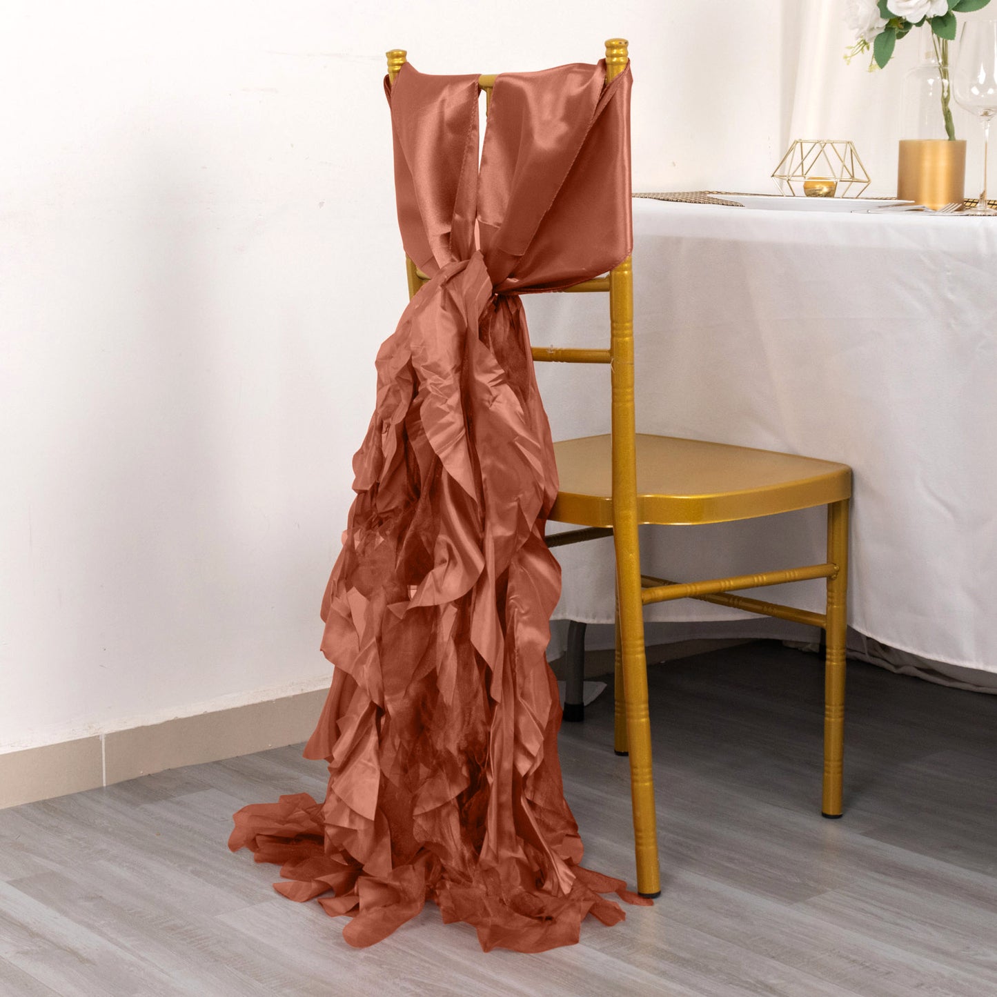 Terracotta chiffon satin chair sash draped on a yellow chair.