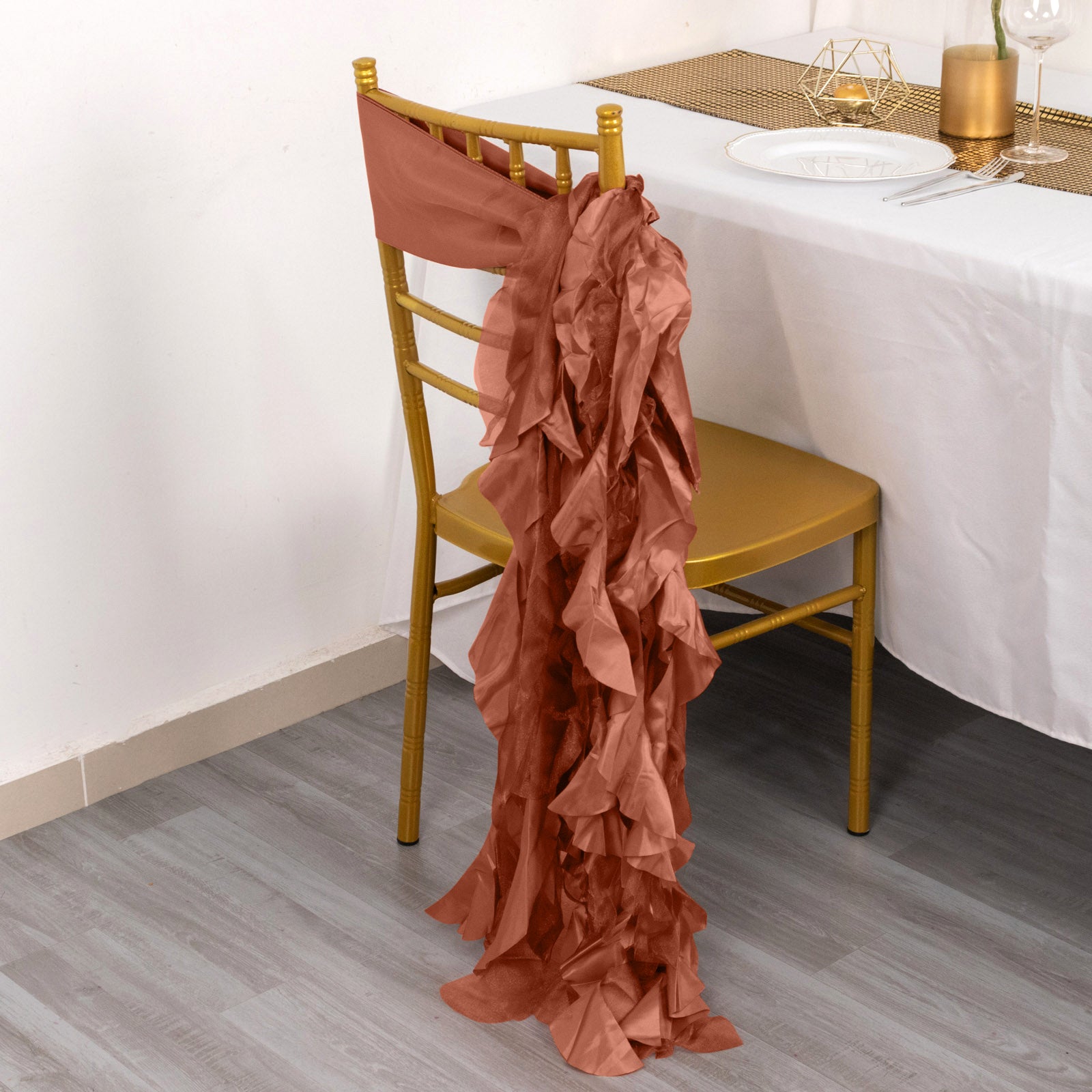 Terracotta curly willow chiffon satin chair sash draped on a gold chair.