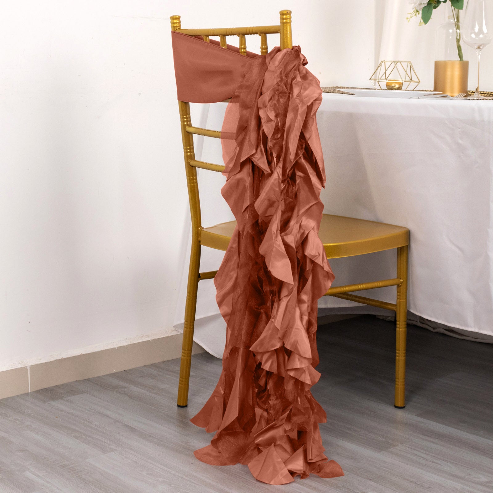 Terracotta curly willow chiffon satin chair sash draped on a gold chair.