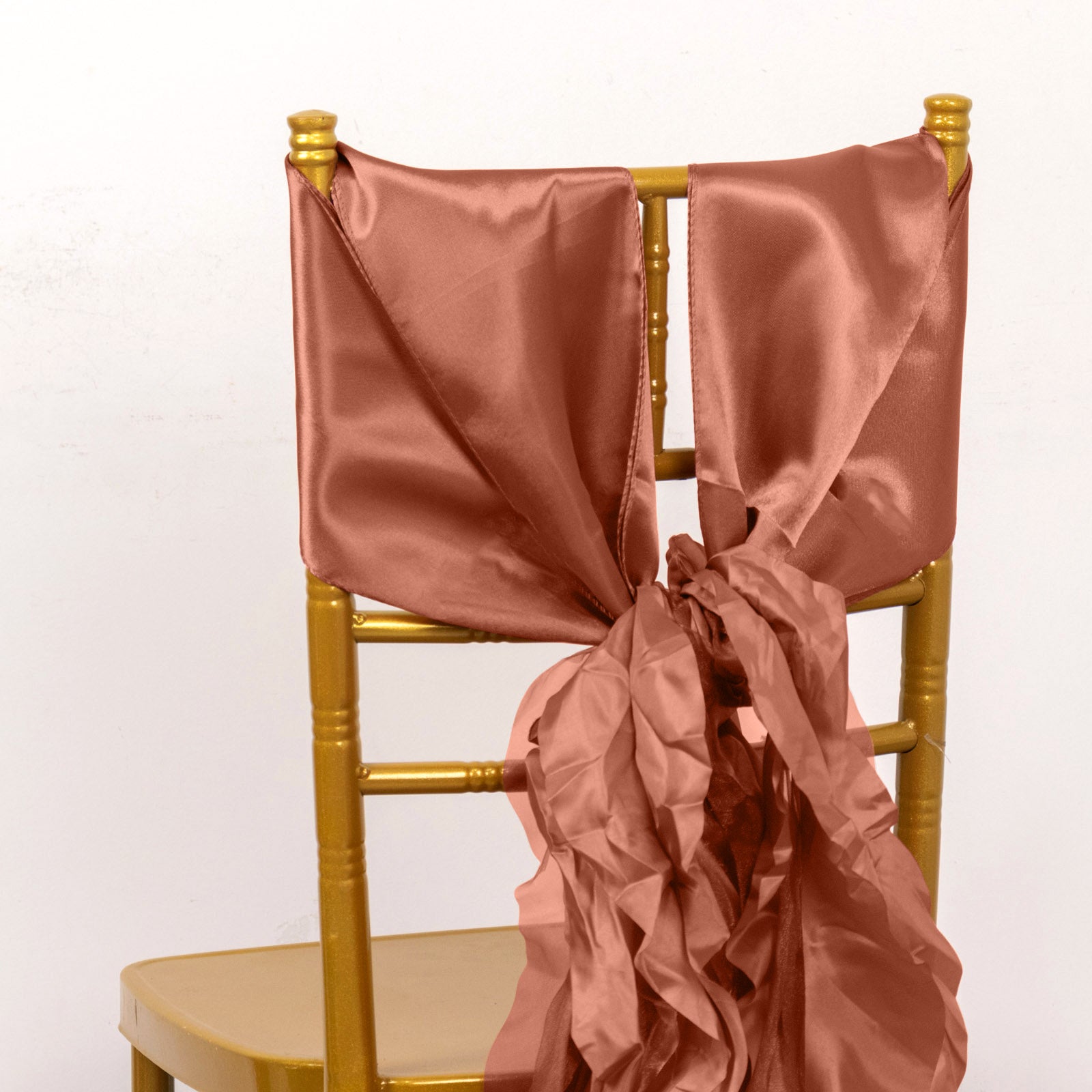 Terracotta curly willow chiffon satin chair sashes on a gold chair.