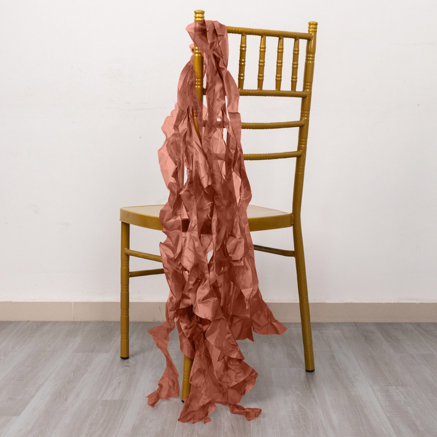 Terracotta curly willow chiffon satin chair sashes draped over a gold chair.