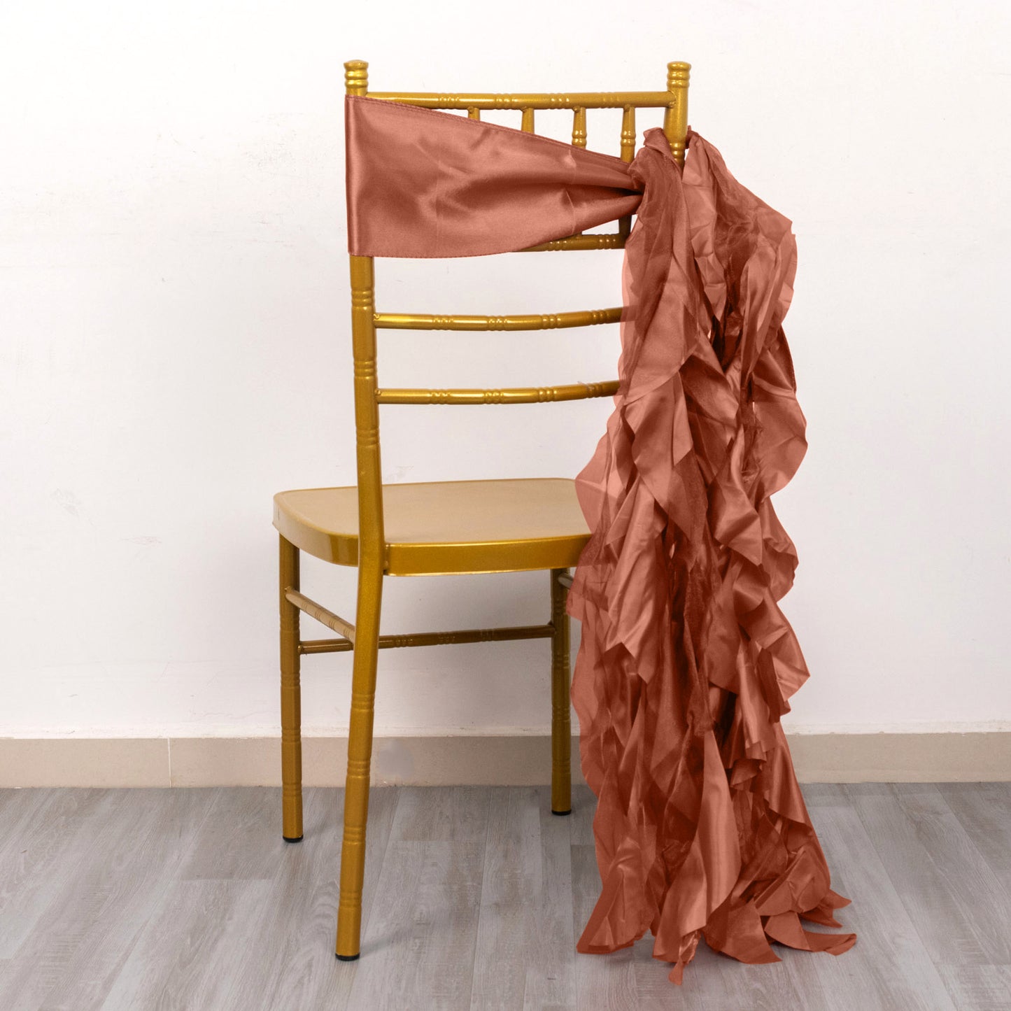 Terracotta curly willow chiffon satin chair sash draped on a gold chair.