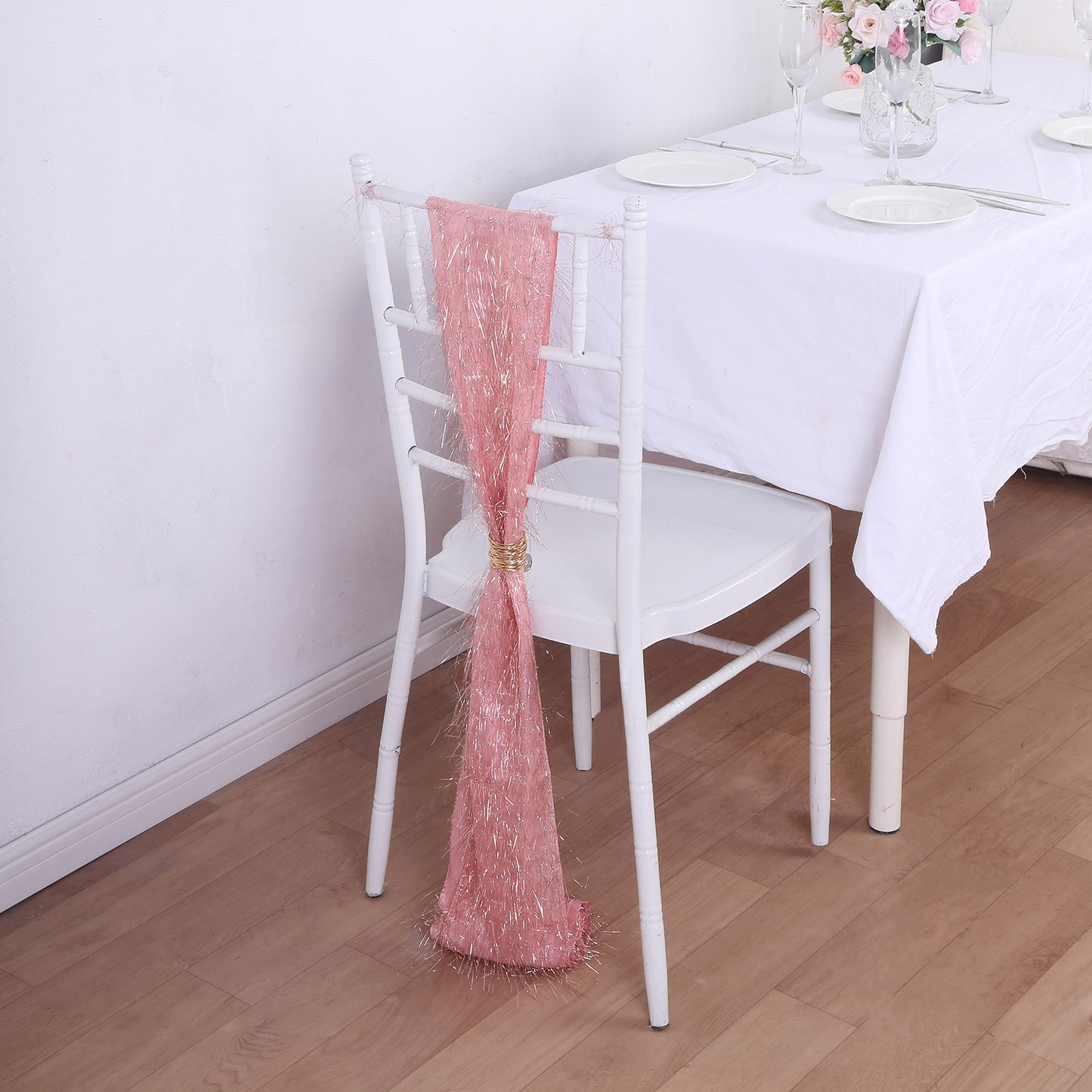 Rose gold metallic fringe tinsel chair sash on a white chair.