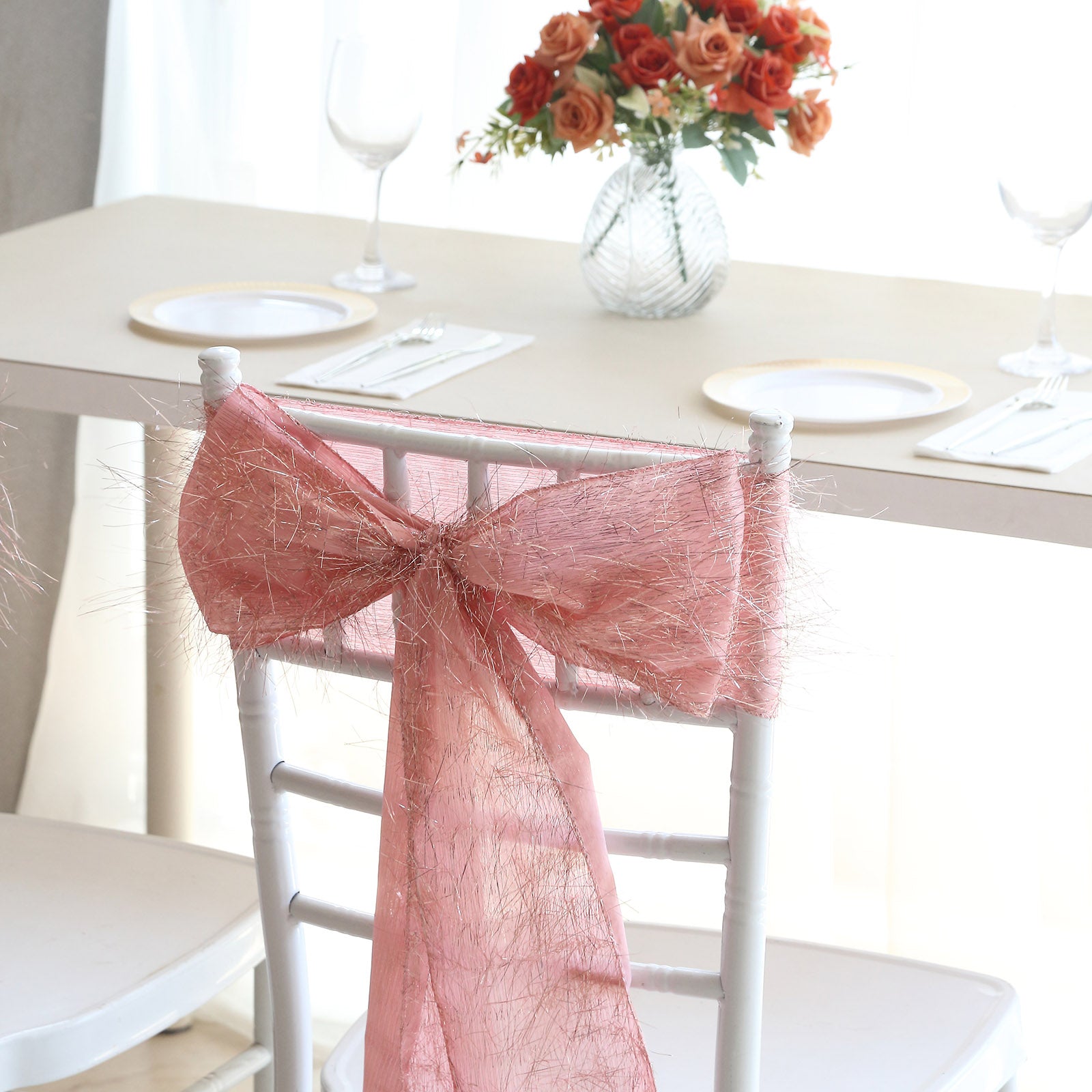 Rose gold metallic fringe tinsel chair sash on a white chair.