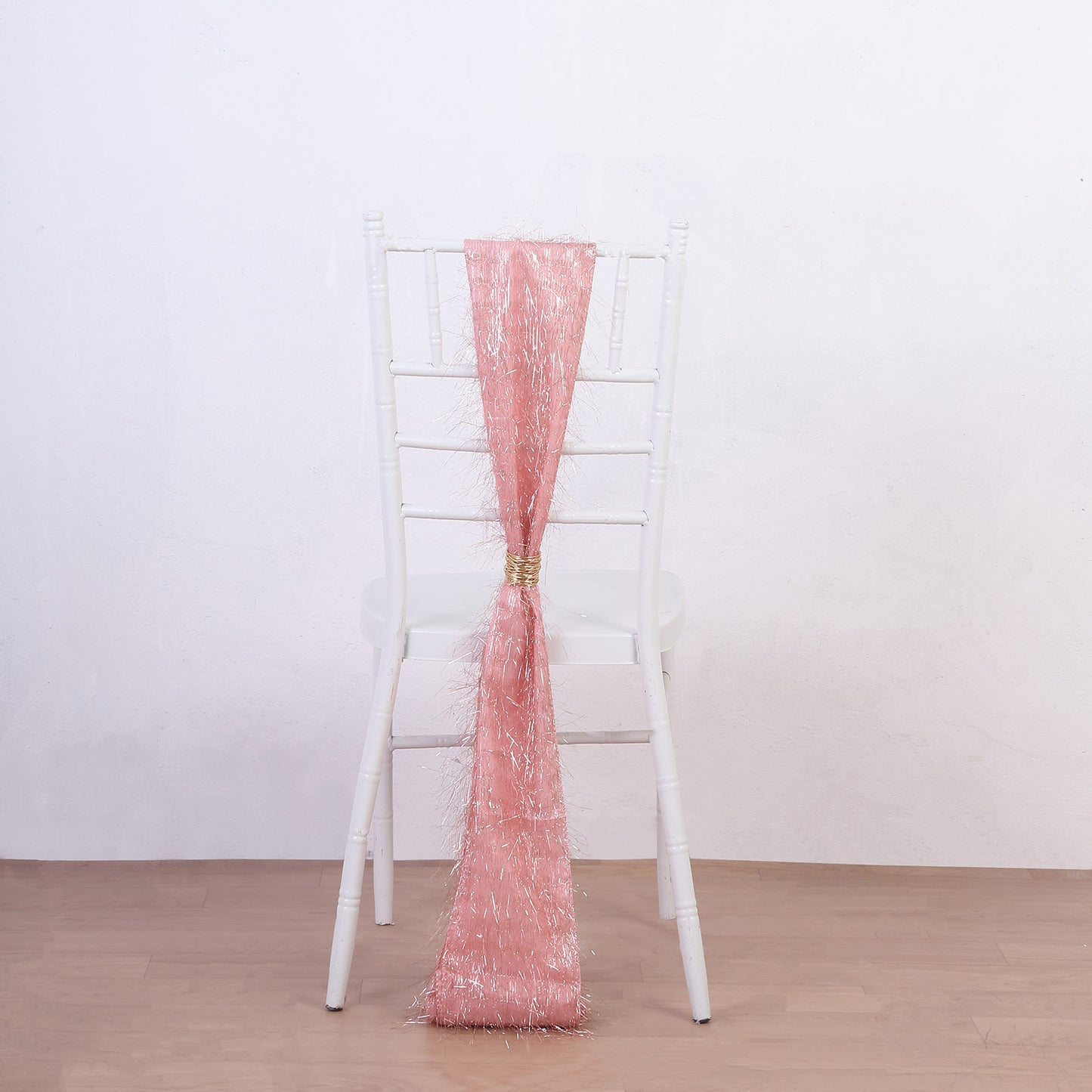 Rose gold metallic fringe tinsel chair sash on a white chair.