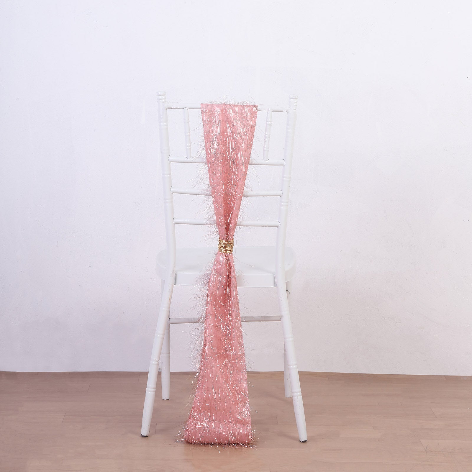 Rose gold metallic fringe tinsel chair sash on a white chair.