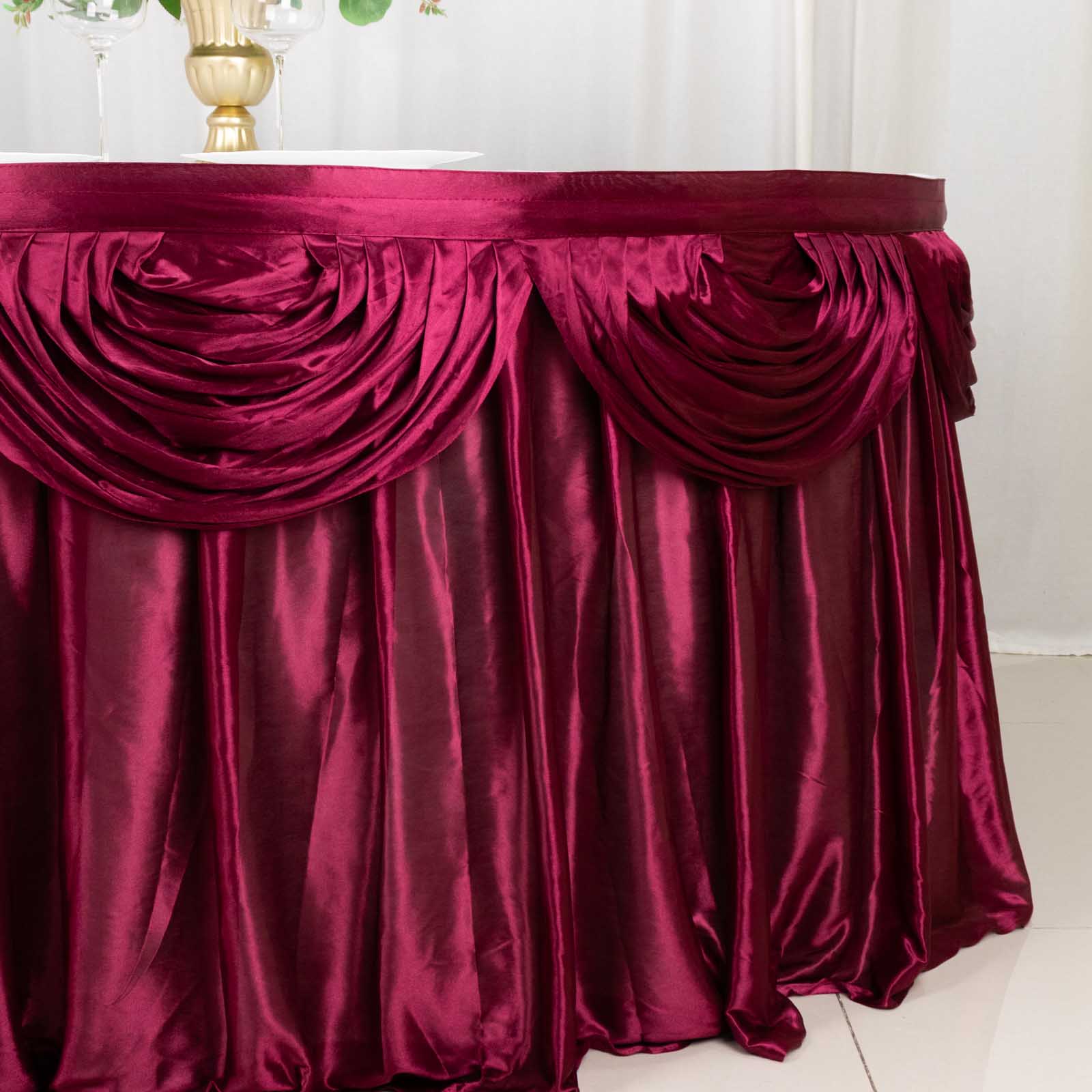 Burgundy pleated satin table skirt draped elegantly around a table.