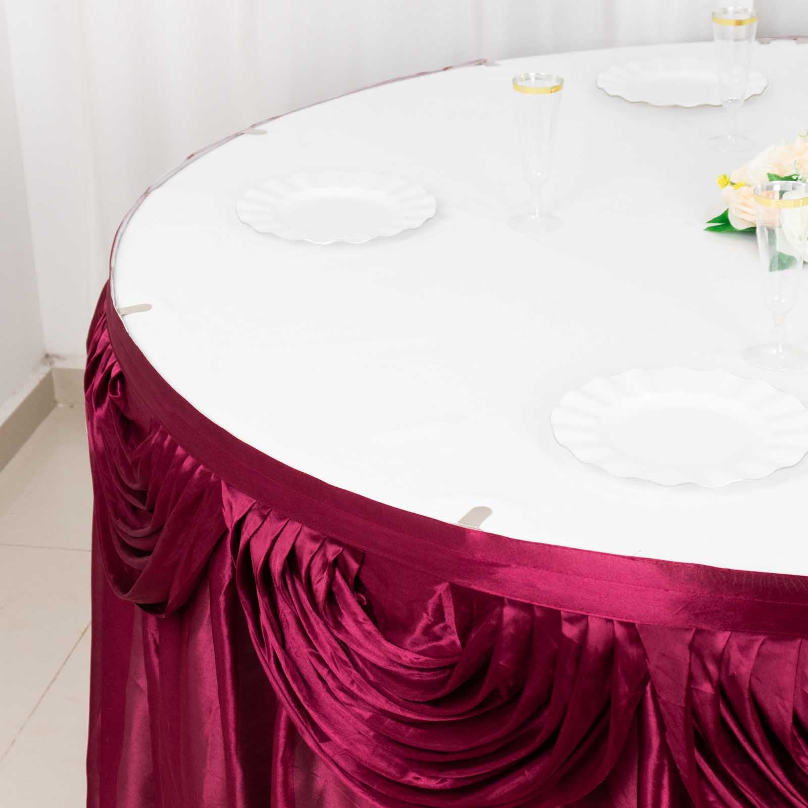 Burgundy pleated satin table skirt draping elegantly around a round table.