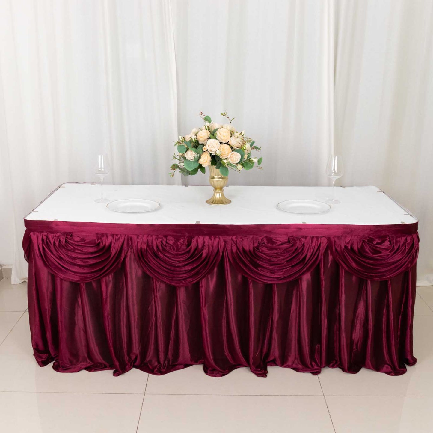 Burgundy pleated satin table skirt draping elegantly around a table.