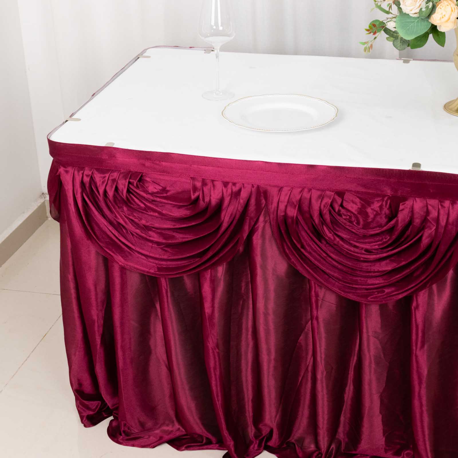 Burgundy pleated satin table skirt draped elegantly on a table.