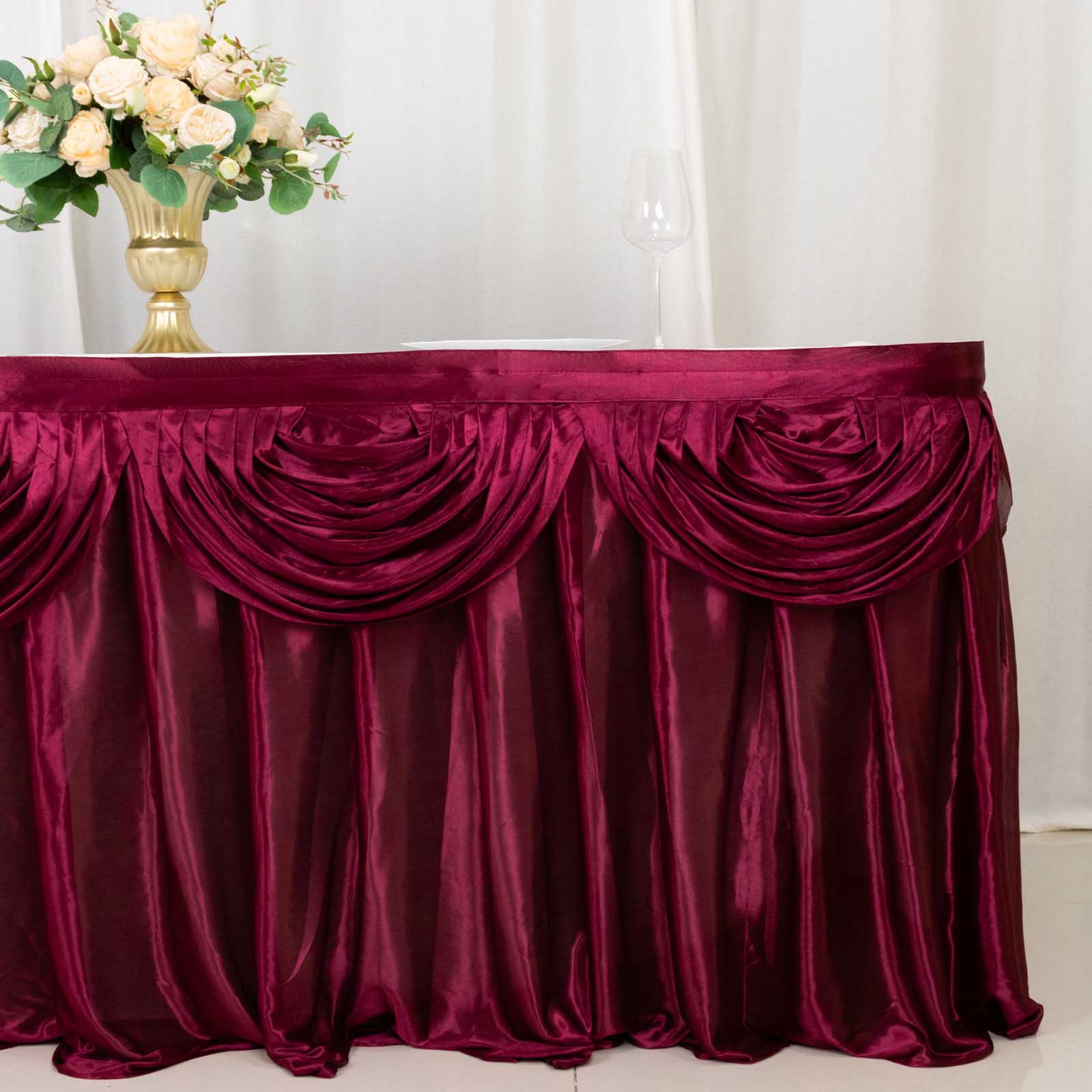 Burgundy pleated satin table skirt draped elegantly on a table.