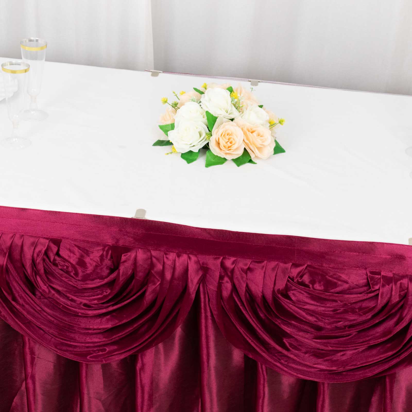 Burgundy pleated satin table skirt draping elegantly around a table.